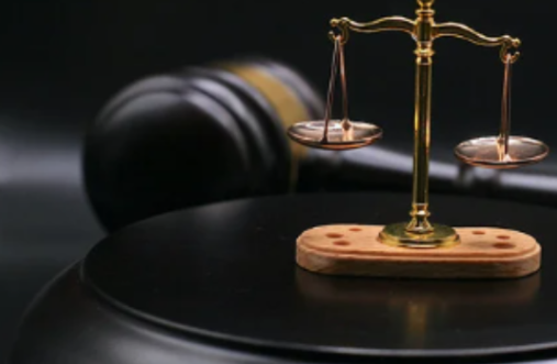 A small scale statue of justice with a gavel in the background.