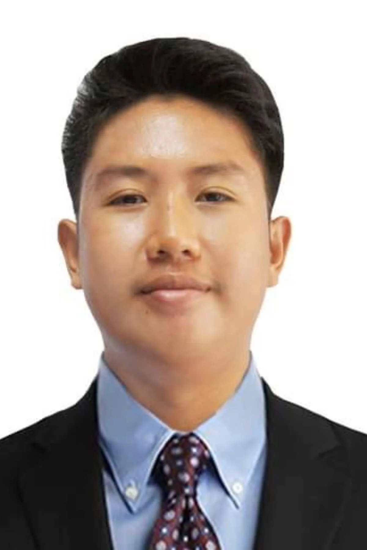 A young man with dark hair wearing a suit, dress shirt, and patterned tie.