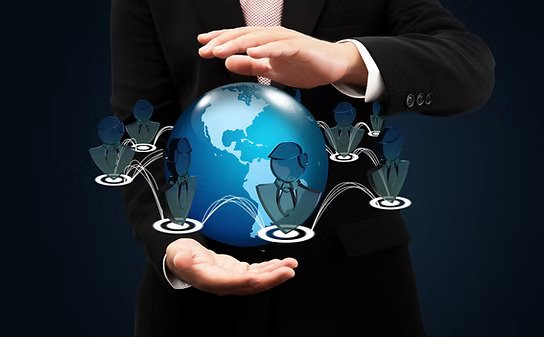 Person in a business suit holding a holographic globe with digital icons of people connected around it, representing global connectivity and networking.