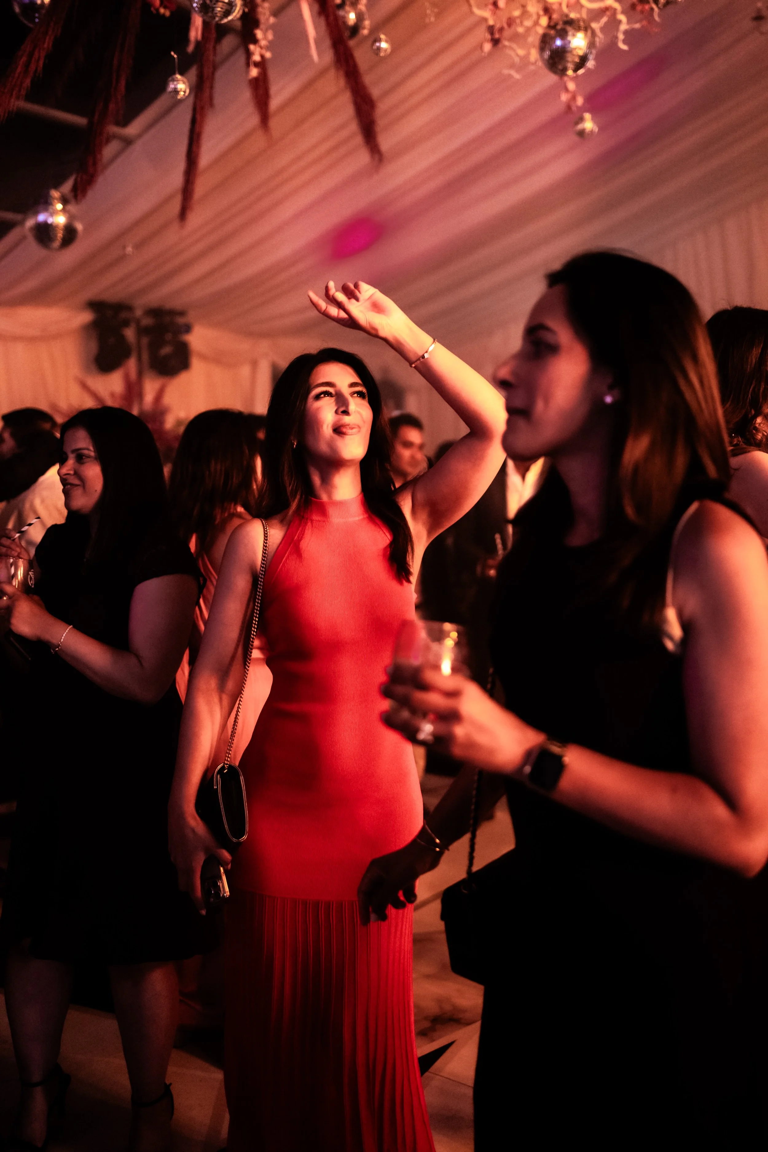 People dancing and socializing at a party or celebration with decorations and lighting.