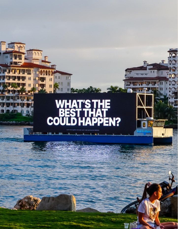 Floating digital billboard on water from a commercial campaign produced by The Aux Co displaying the message What’s the best that could happen.