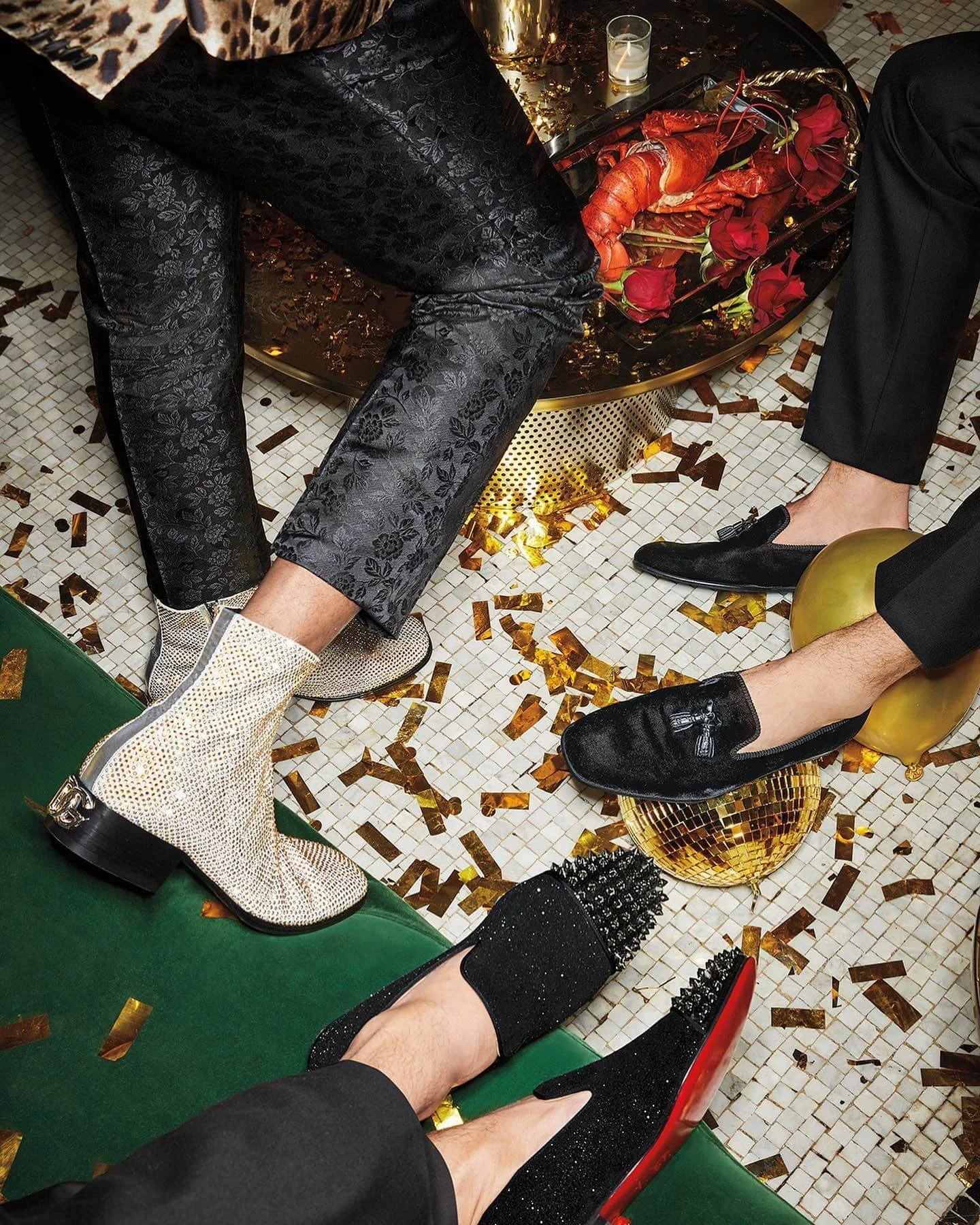 Fashionably dressed people with shiny, embellished shoes sitting on colorful furniture amid gold confetti and decor at a party or celebration.
