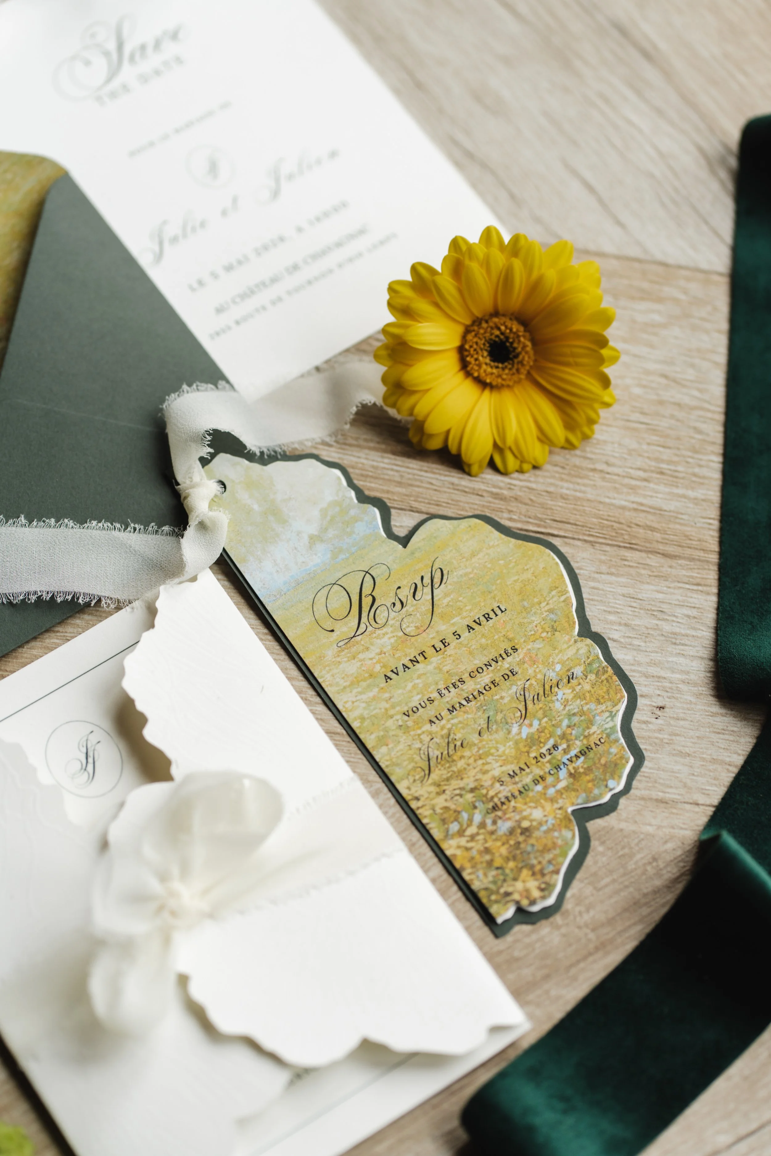 Une invitation de mariage avec une fleur jaune et un fond en bois, accompagnée de rubans blancs et d'un menu ou RSVP stylisé.
