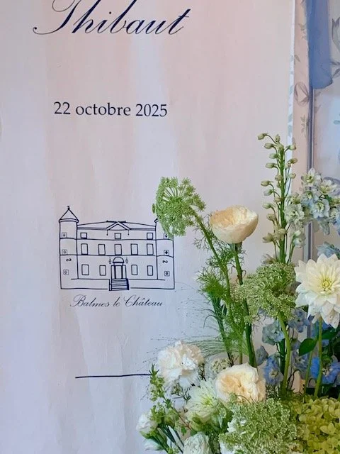 Une affiche avec une illustration d'un château et des fleurs blanches et vertes en premier plan, avec du texte en français indiquant une date, le lieu et un nom.