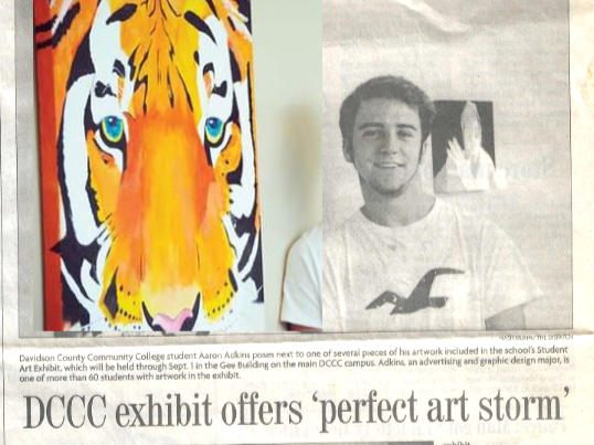 A large mural of a tiger's face painted with bold colors and black stripes, and a black-and-white photograph of a smiling young man wearing a white T-shirt.