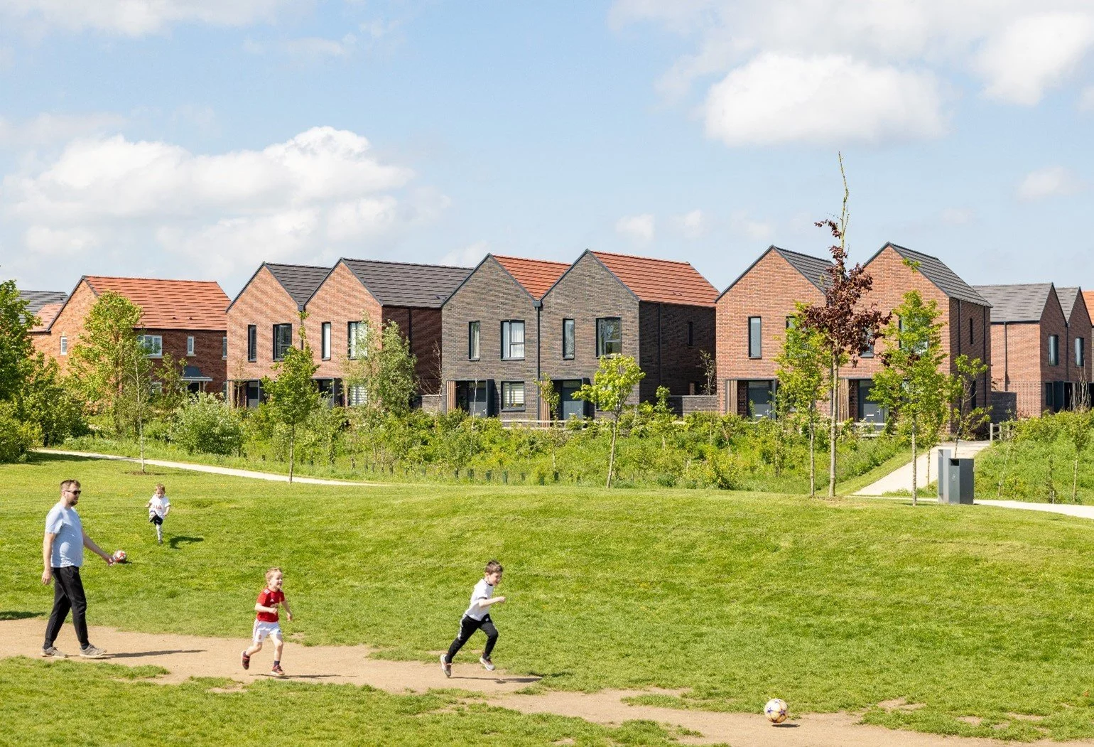 Forest Edge, Wood End precedent image, with children playing in a green area and houses in the background.