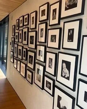 Gallery wall with multiple black-and-white framed photographs arranged in an overlapping display.