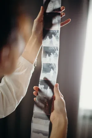 Person holding an x-ray film with multiple images, including a skull and a hand.
