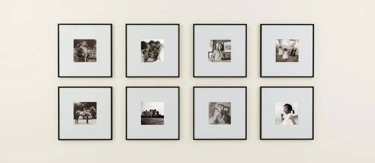 A wall with eight black-and-white framed photographs arranged in two rows of four.