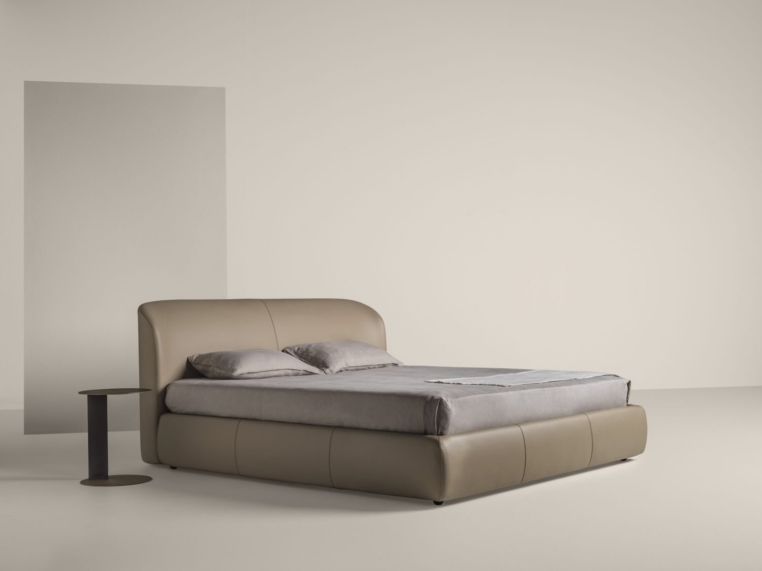 Italian Loren bed by Frag with elegant curved beige leather headboard at ArkNova Interiors Paphos showroom in Cyprus