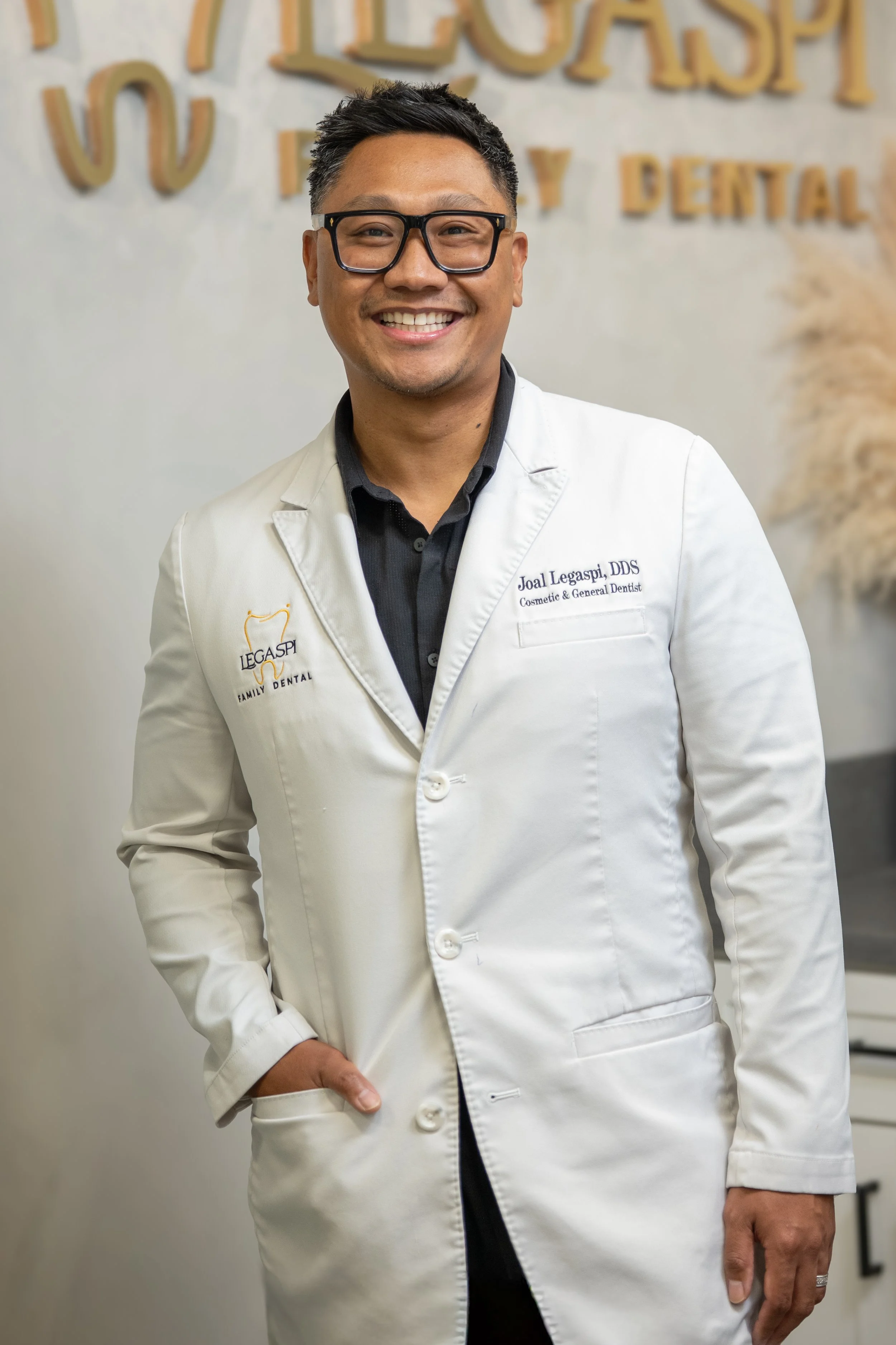 Smile of a male dentist in a white coat standing in dental office.