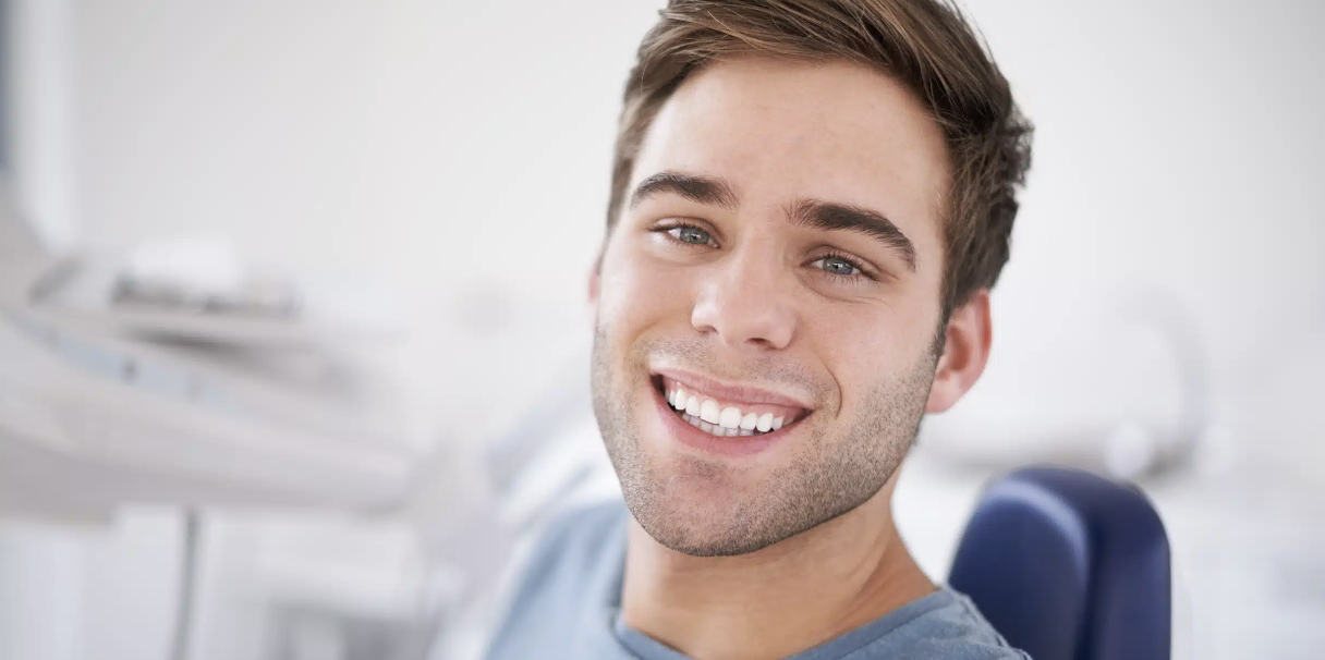 Smiling young man sitting in a dental chair at a dentist's office