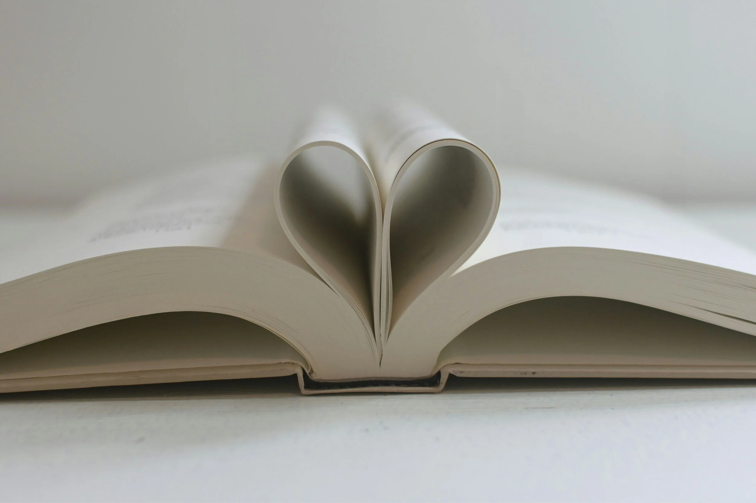 An open book with its pages folded into a heart shape
