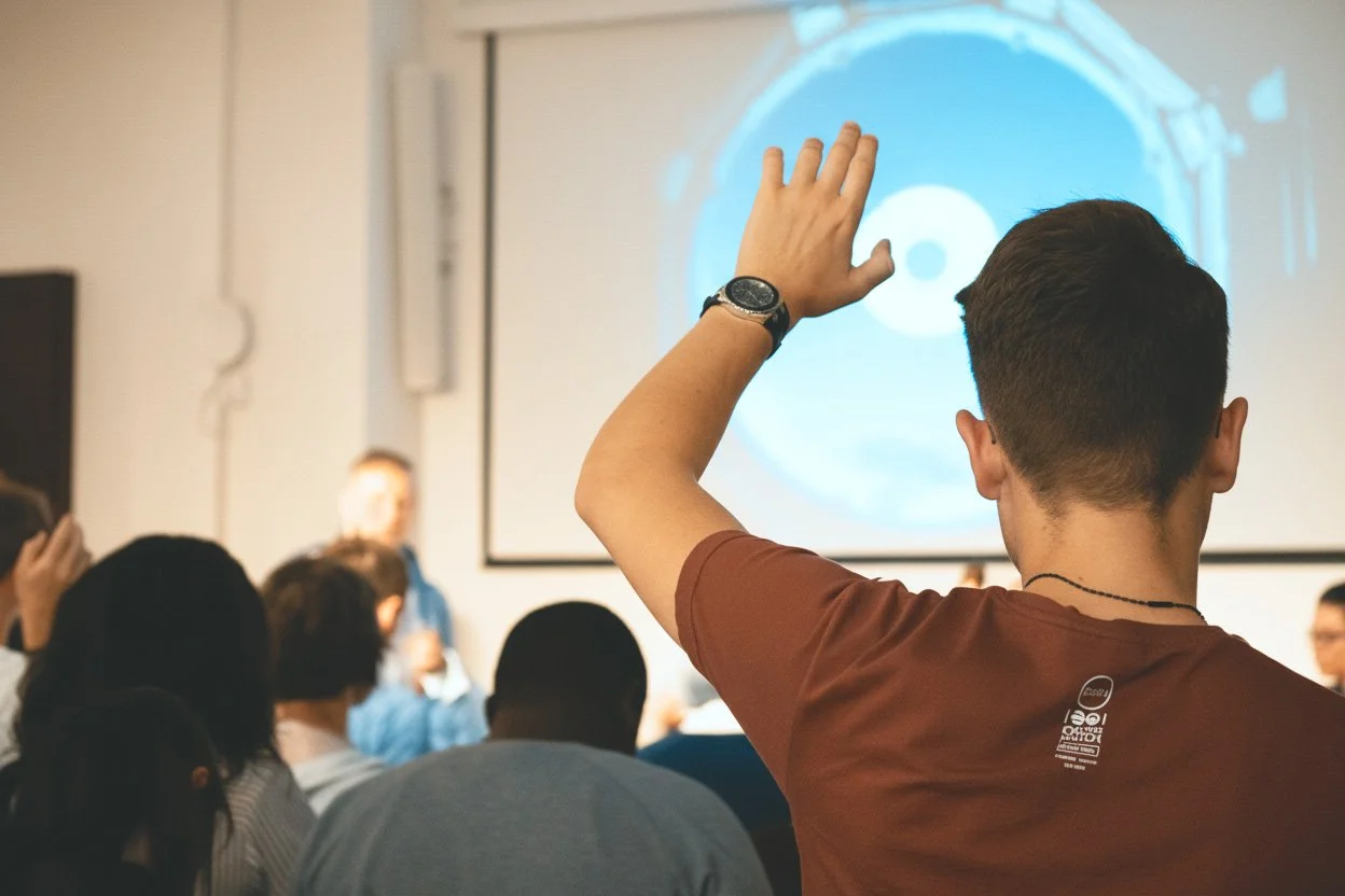 Back view of a male in audience raising his hand during a company briefing