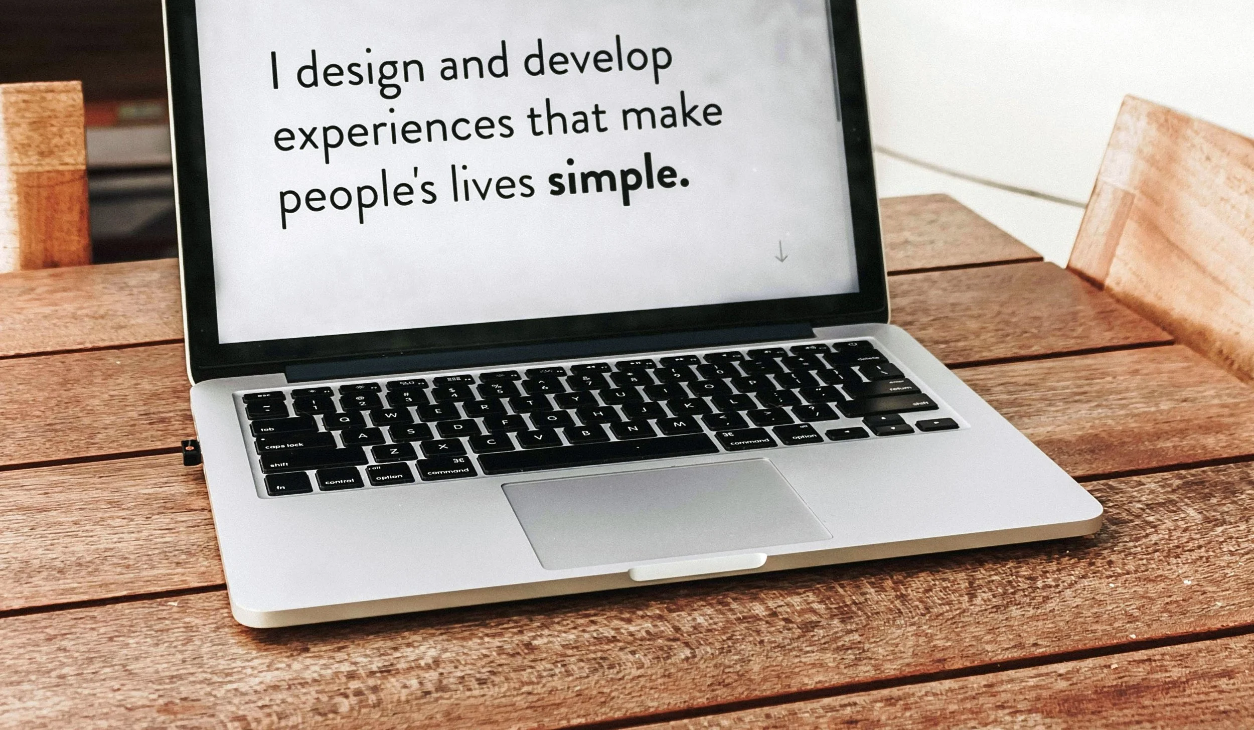 "Laptop screen displaying the text: 'I design and develop experiences that make people's lives simple.'"