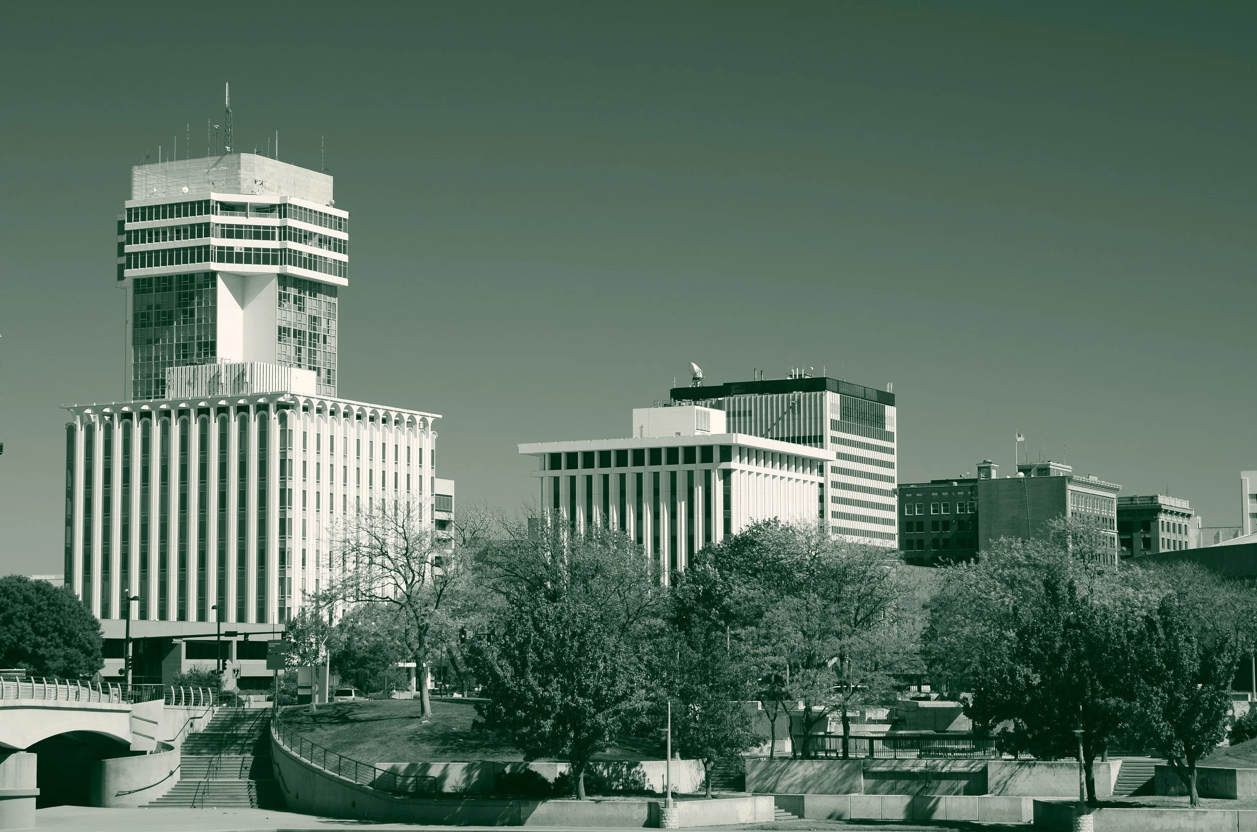 Downtown Wichita, Kansas, seen across a riverside park, with the city's mid-century office towers rising behind trees in autumn color.
