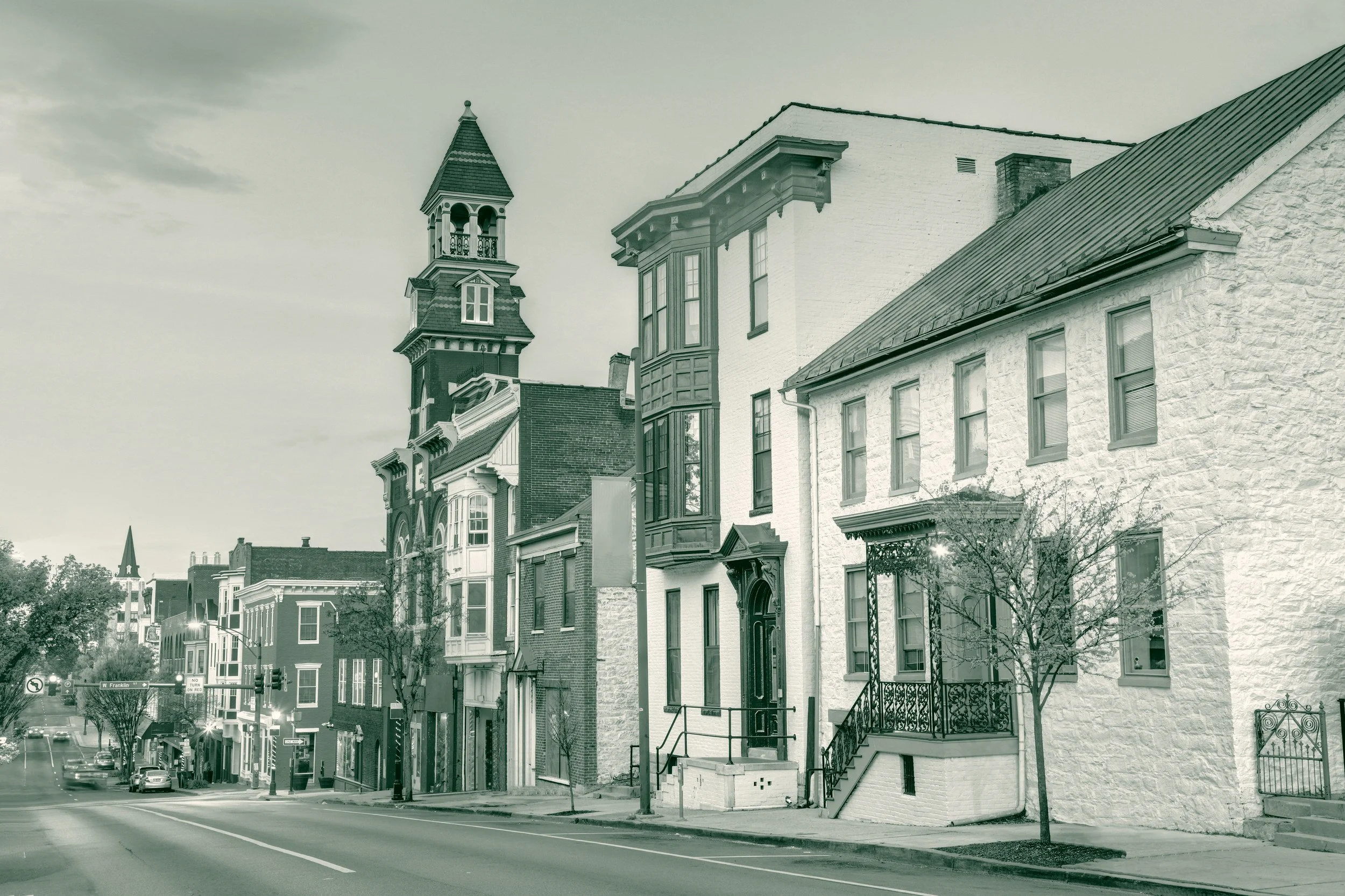 Downtown Hagerstown, Maryland at dusk, with brick and stone rowhouses lining the street beneath a Victorian bell tower.