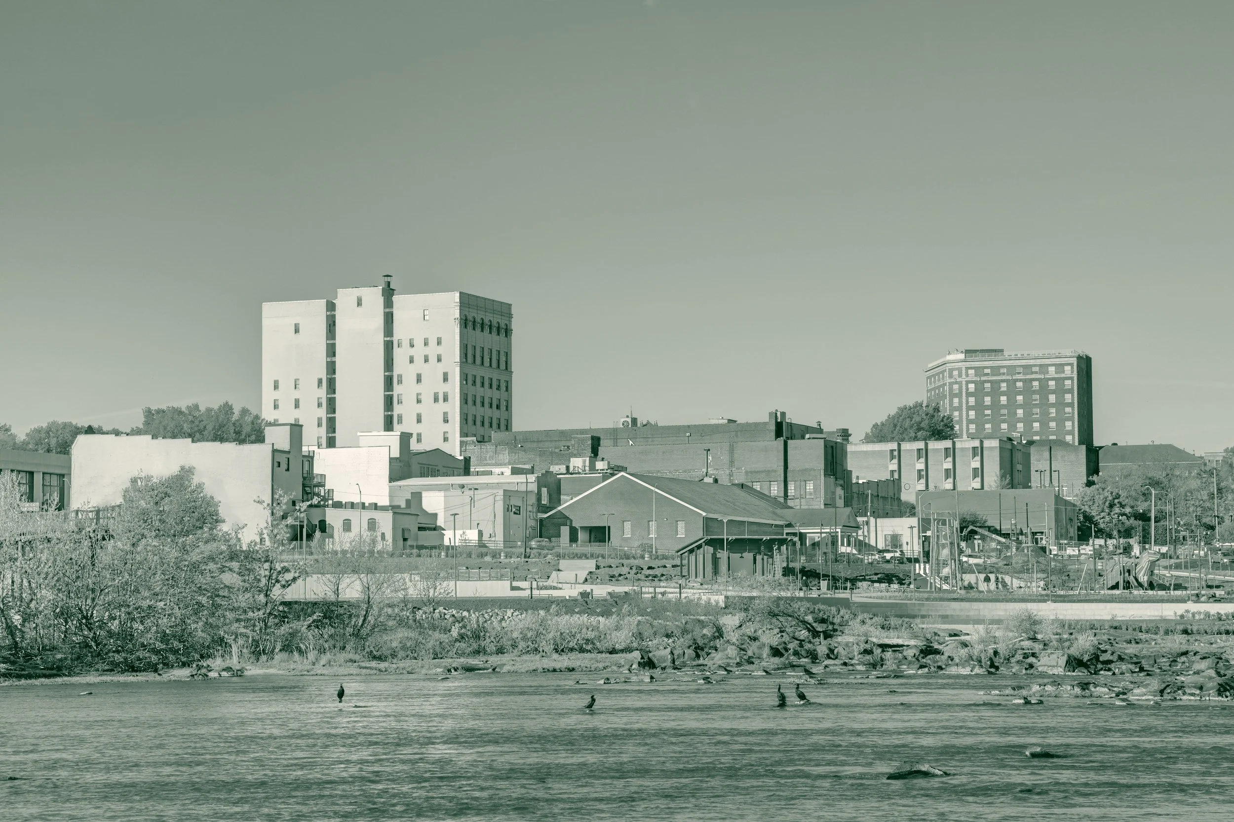 Downtown Danville, Virginia, seen across the Dan River, with brick mill and warehouse buildings along the waterfront.