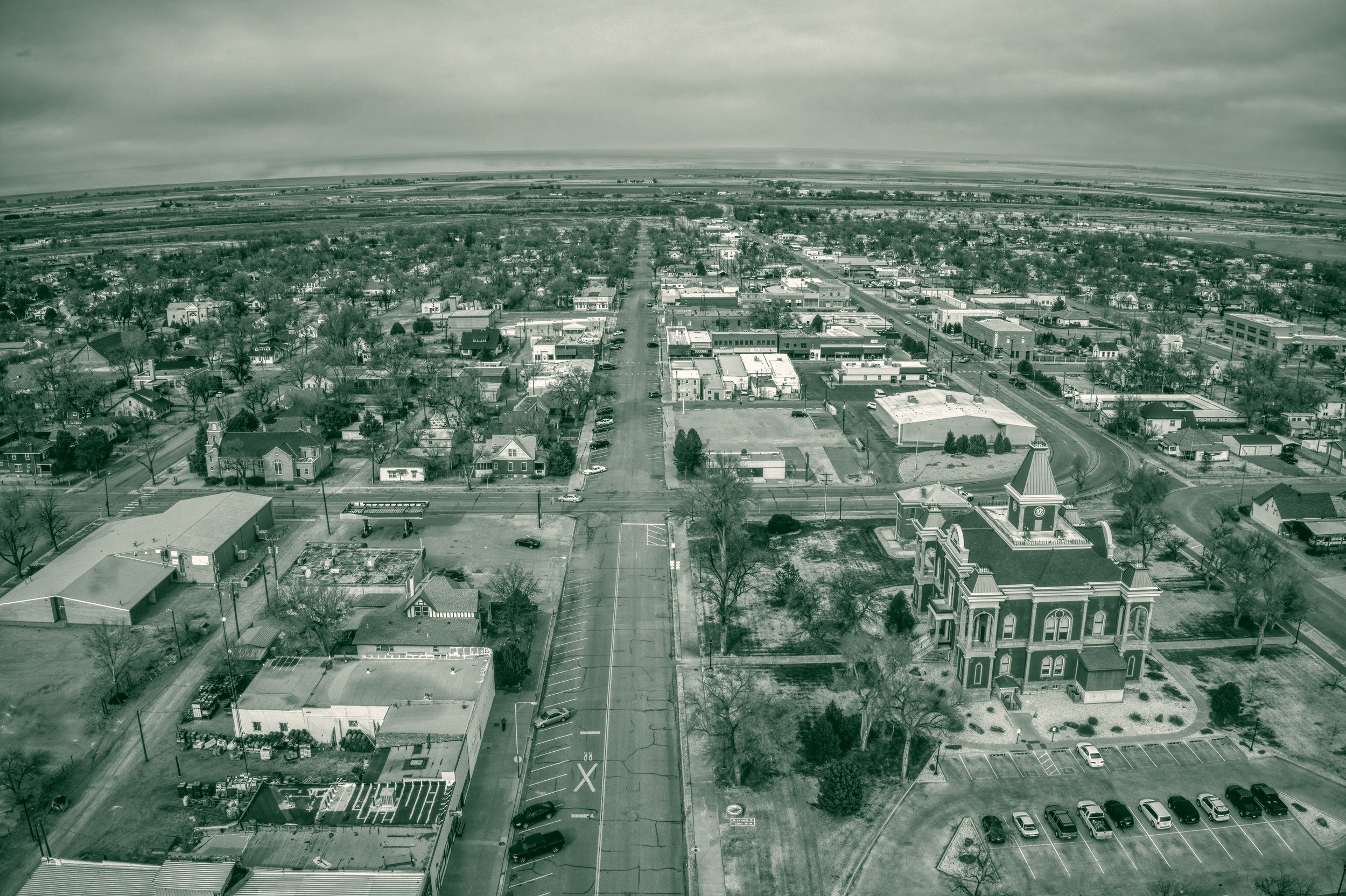 Aerial view down the main street of Las Animas, Colorado, with the historic Bent County Courthouse in the foreground and open farmland stretching to the horizon.