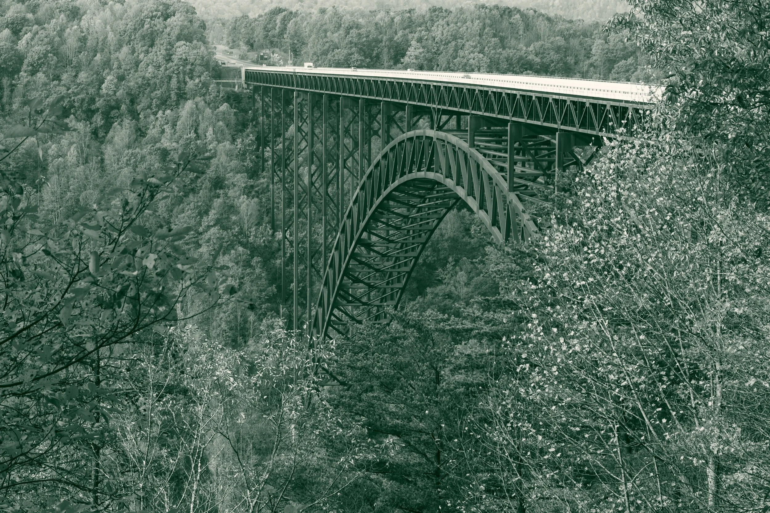 The New River Gorge Bridge, a steel arch bridge, spans the wooded gorge in autumn in Fayette County, West Virginia.