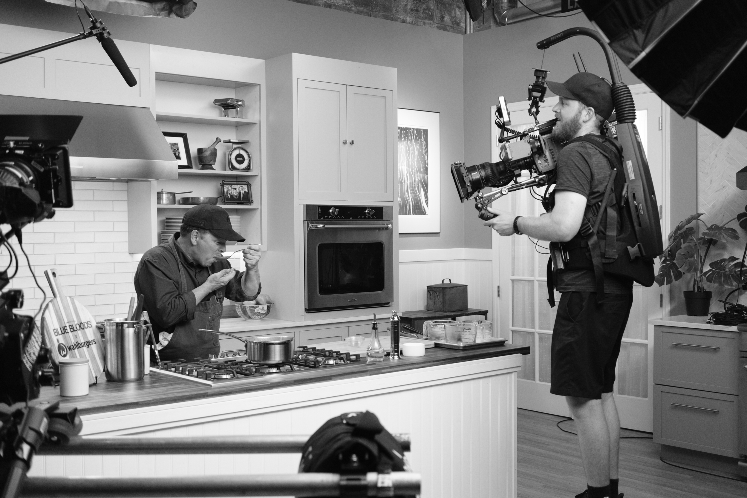 A behind-the-scenes shot of a kitchen scene being filmed by Andrew Henkelman on the set of Blue Bloods: Family Recipes. A multi-channel cooking series with CBS/Blue Bloods and Wahlburgers.
