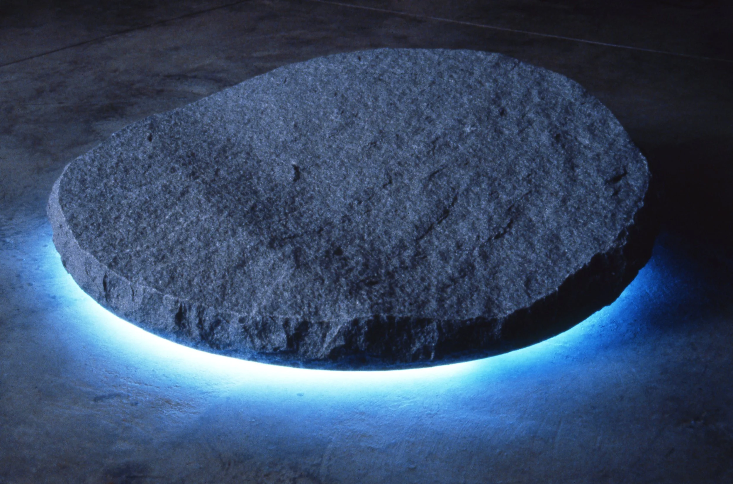 A circular stone with neon lighting underneath that glows blue in a dark room.