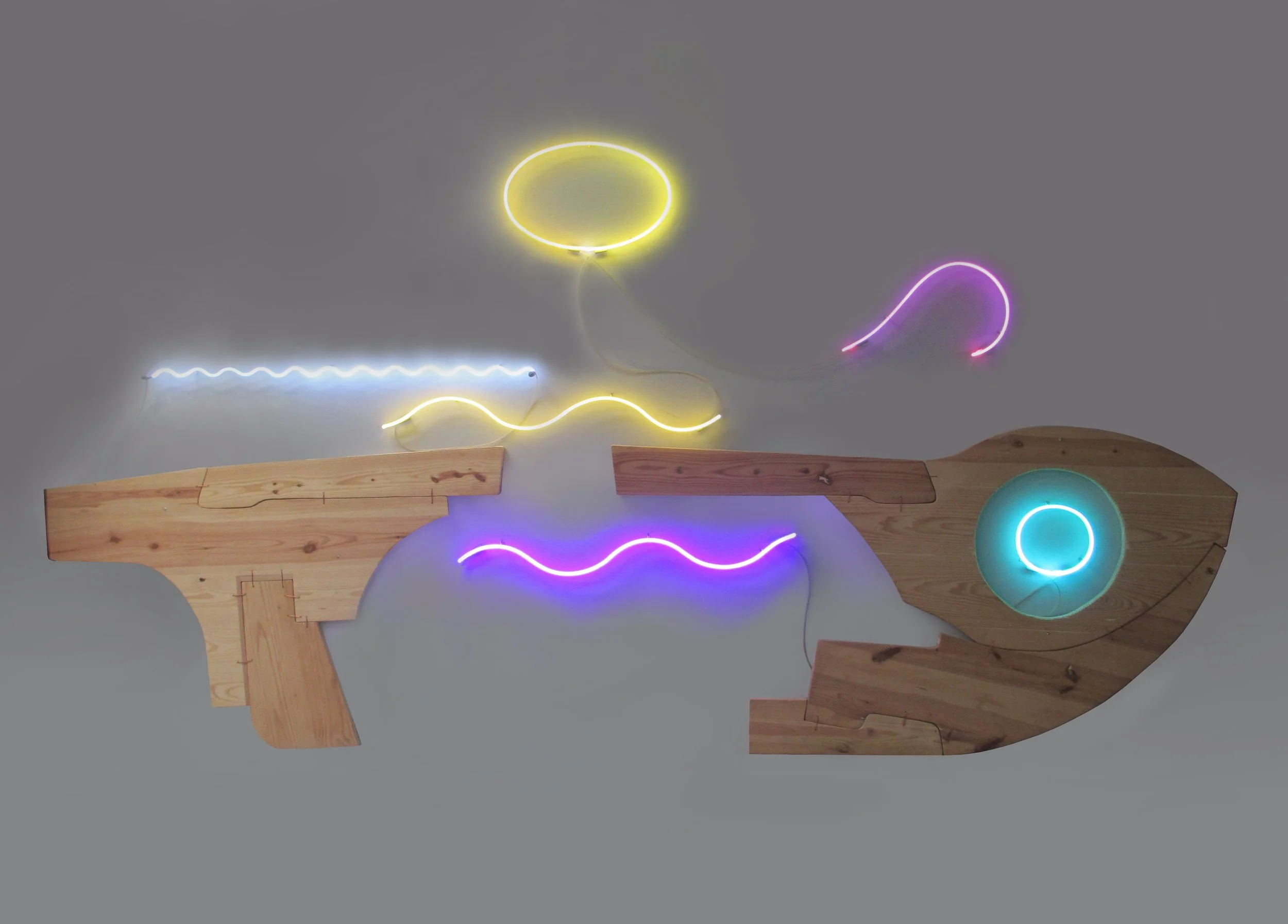 Mixed media artwork resembling a stylized handgun with neon lights in yellow, blue, purple, and pink, mounted on a wooden base.