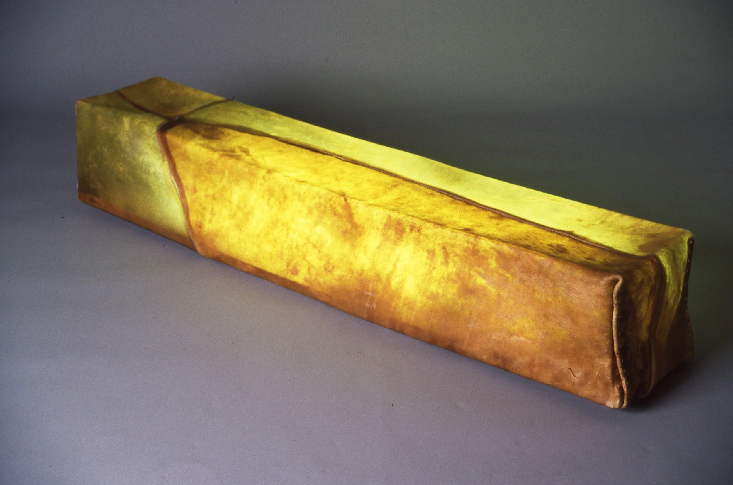 Lighting fixture resembling a yellow and brown leaf with textured surface.