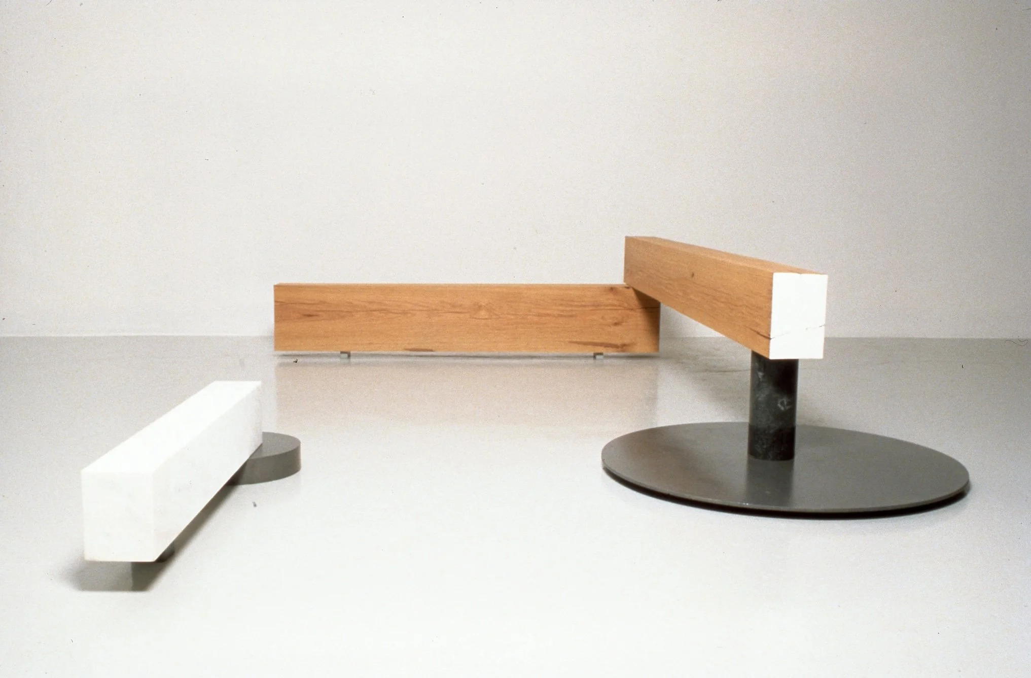 Abstract sculpture with wooden and metal elements on a white surface.