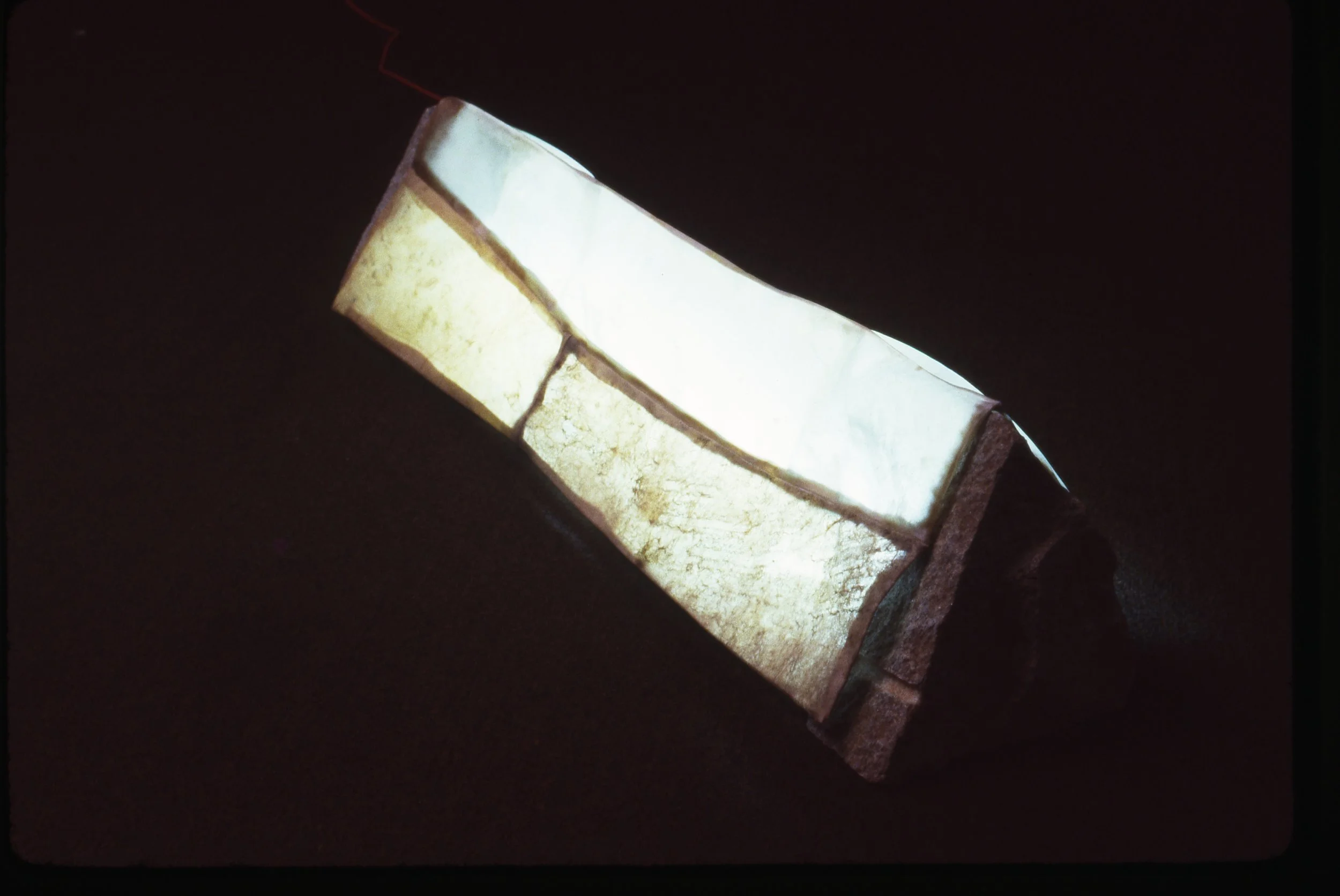 A close-up of illuminated glass bricks on a dark background, arranged in a curved pattern.