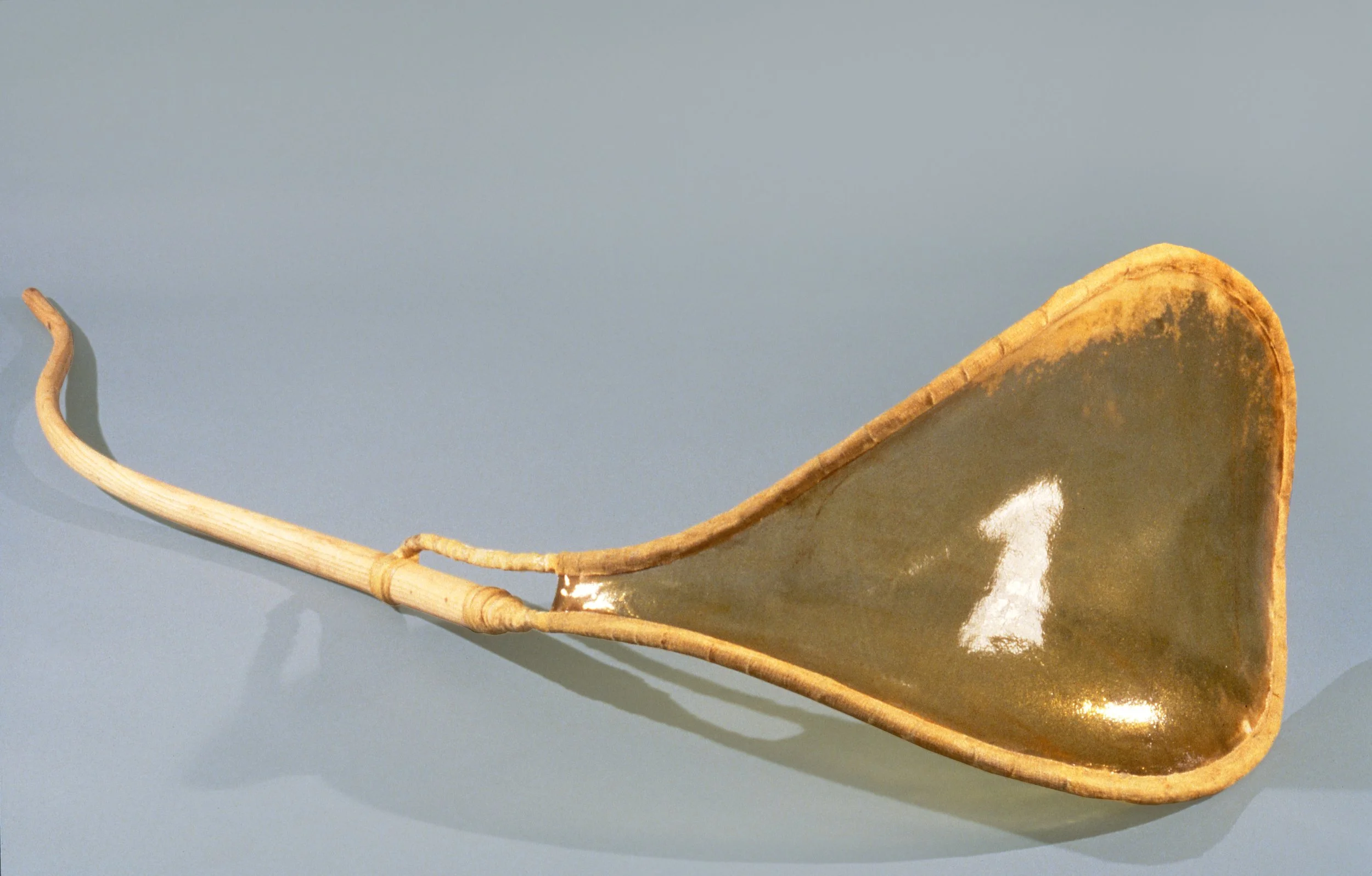 A long, curved wooden handle, placed on a light blue surface.