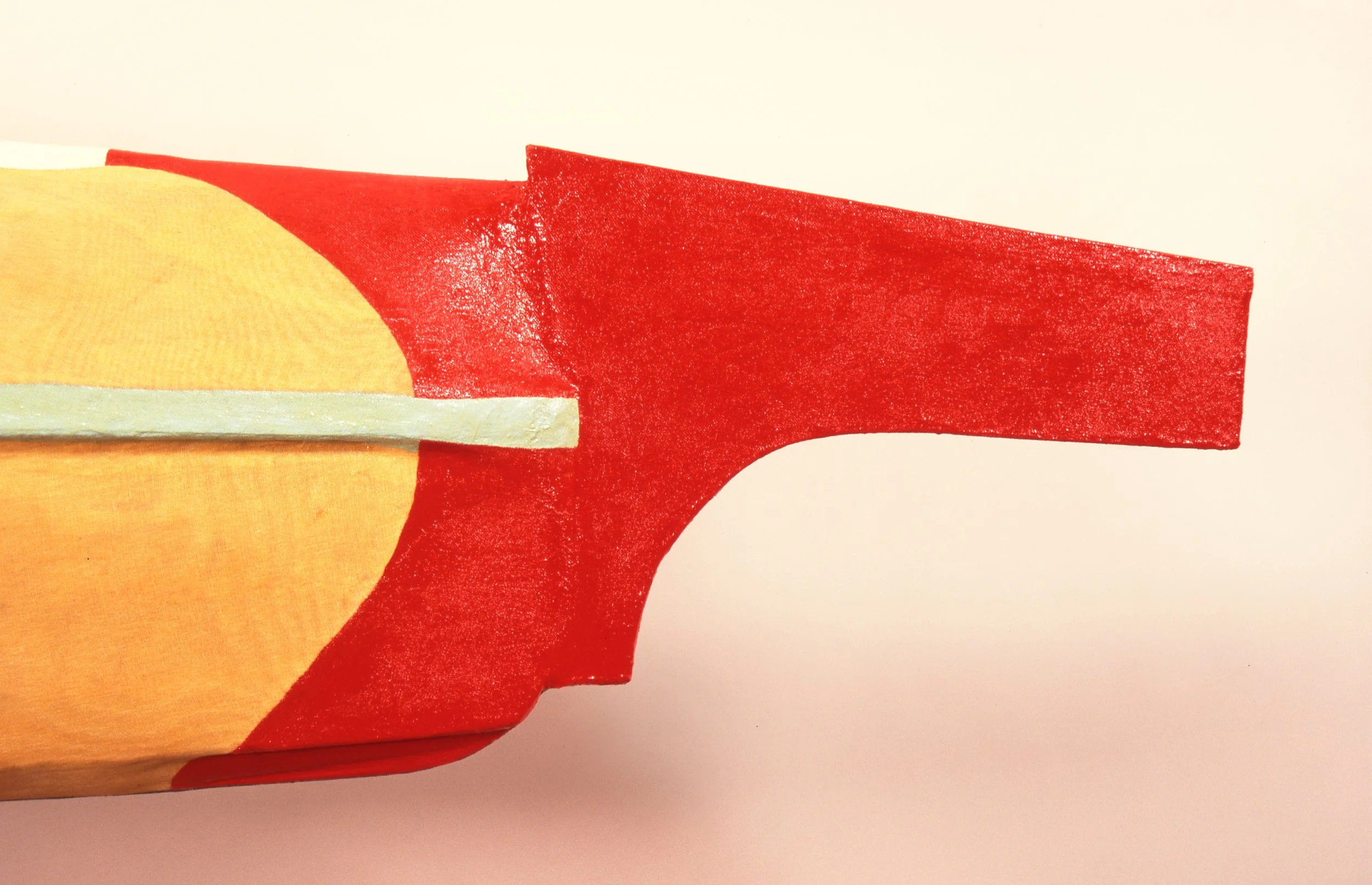 Close-up of a wooden toy with red and yellow parts, resembling a stylized animal or object.