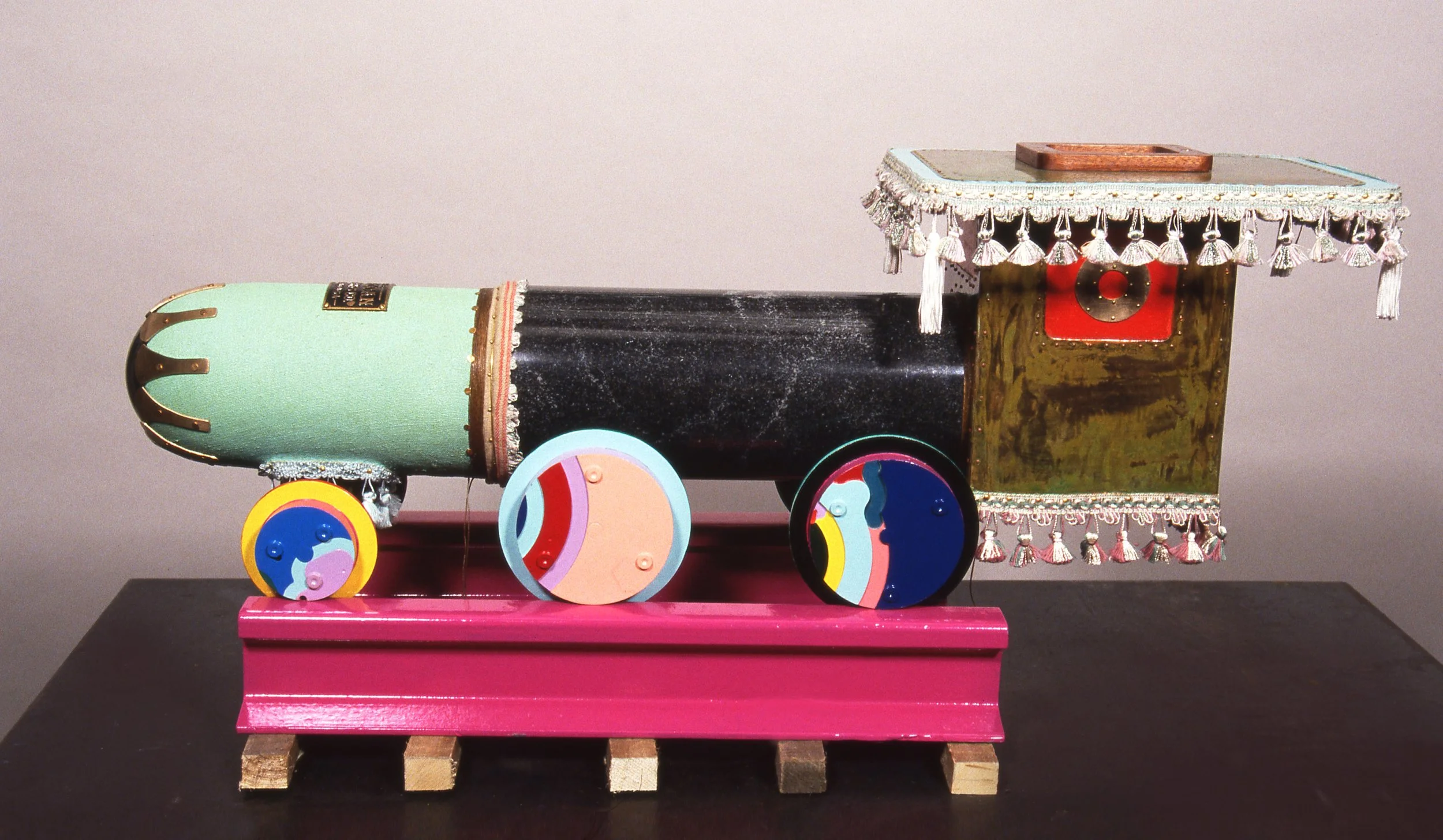 Colorful handmade toy train with wheels on a wooden stand.