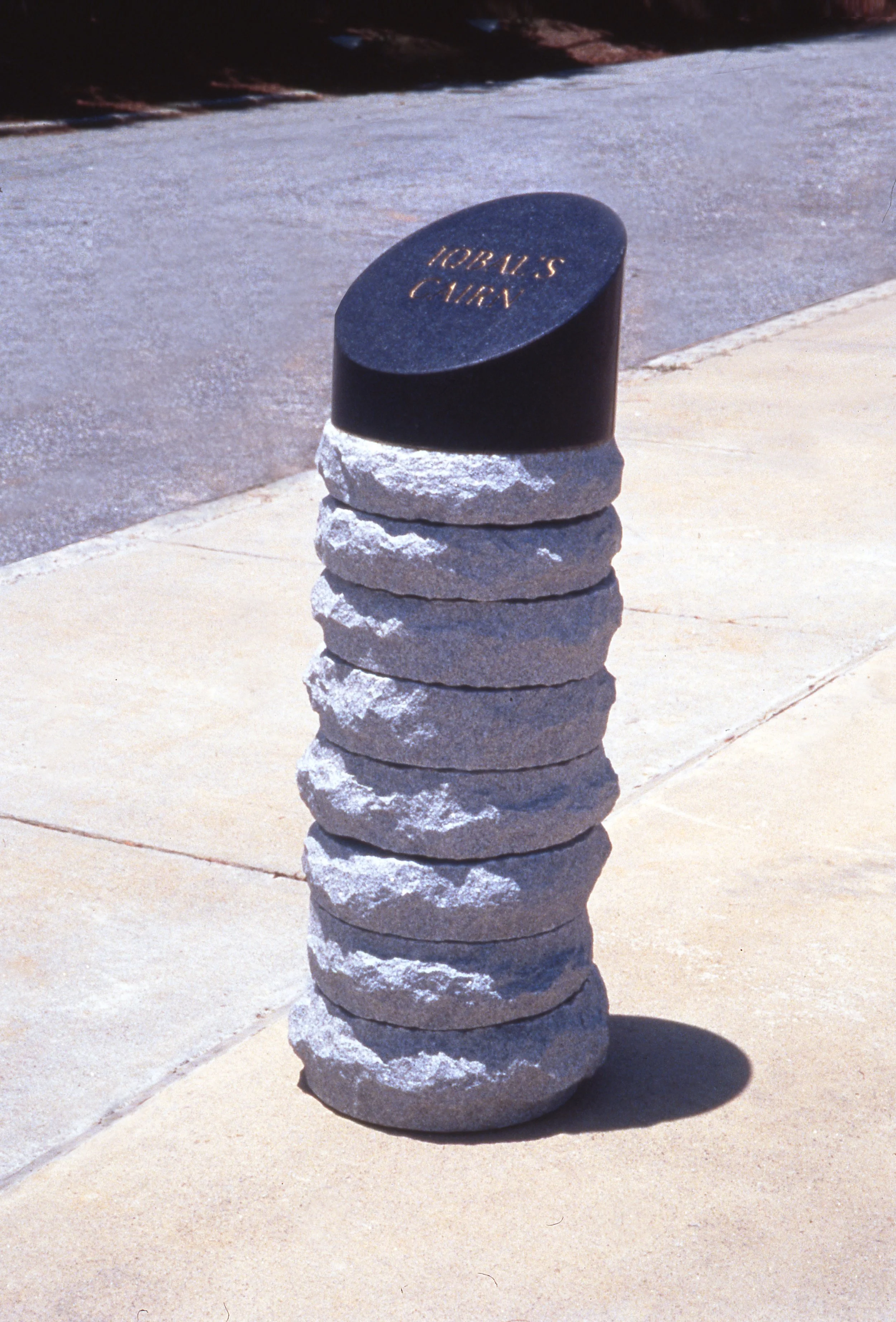 A stack of 10 uneven gray rocks with a rounded black stone on top that has the words "TORY N'S CARRY" engraved in gold.