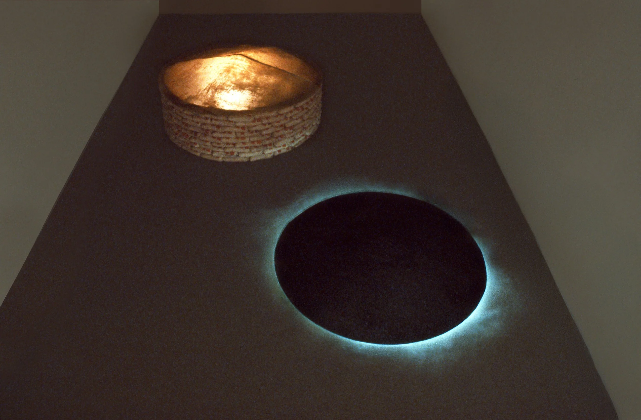 A table with a circular opening that creates a solar eclipse effect, and a basket with a light on top.