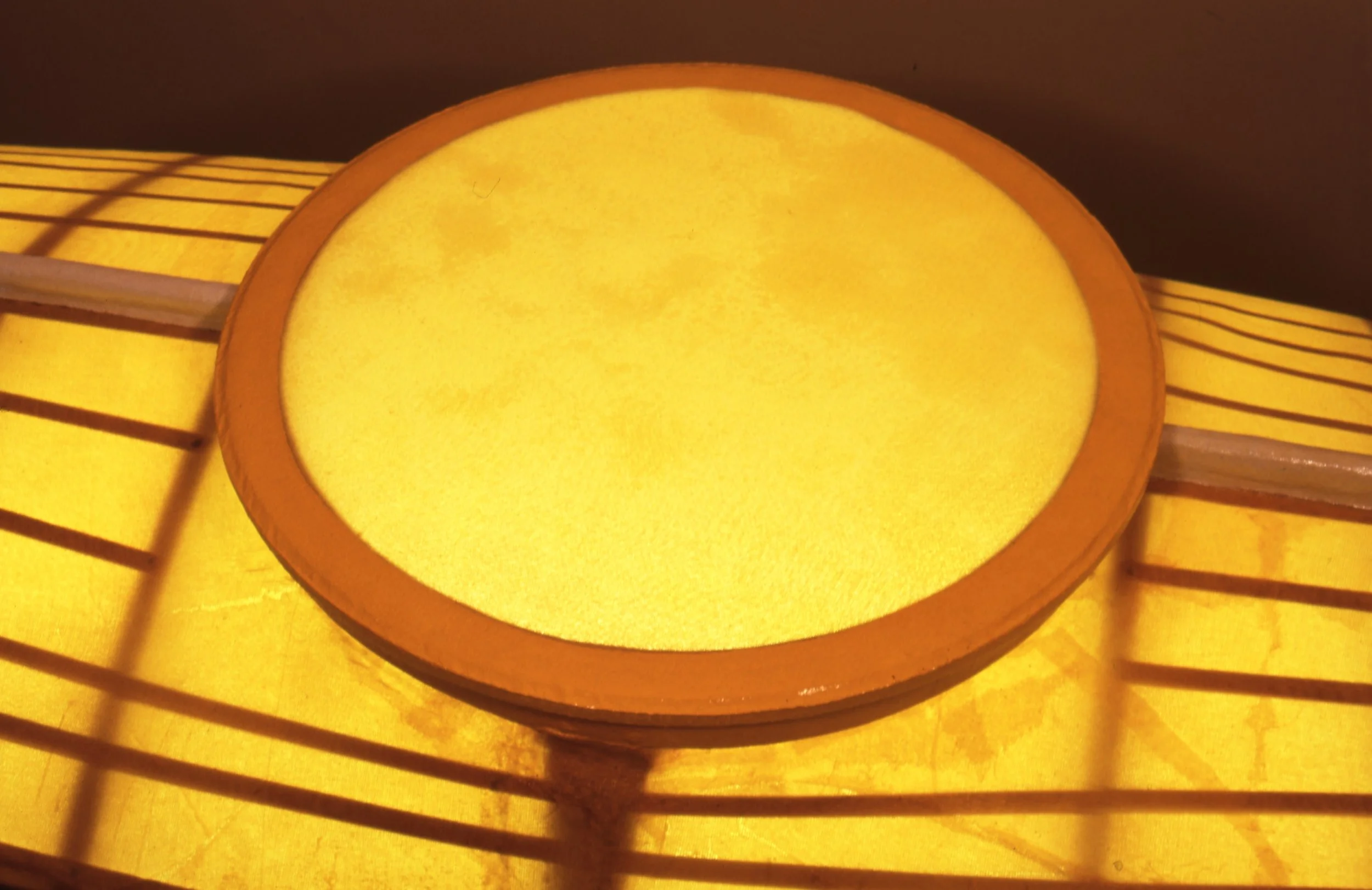 Close-up of a yellow paper lantern with a wooden frame and horizontal slats.