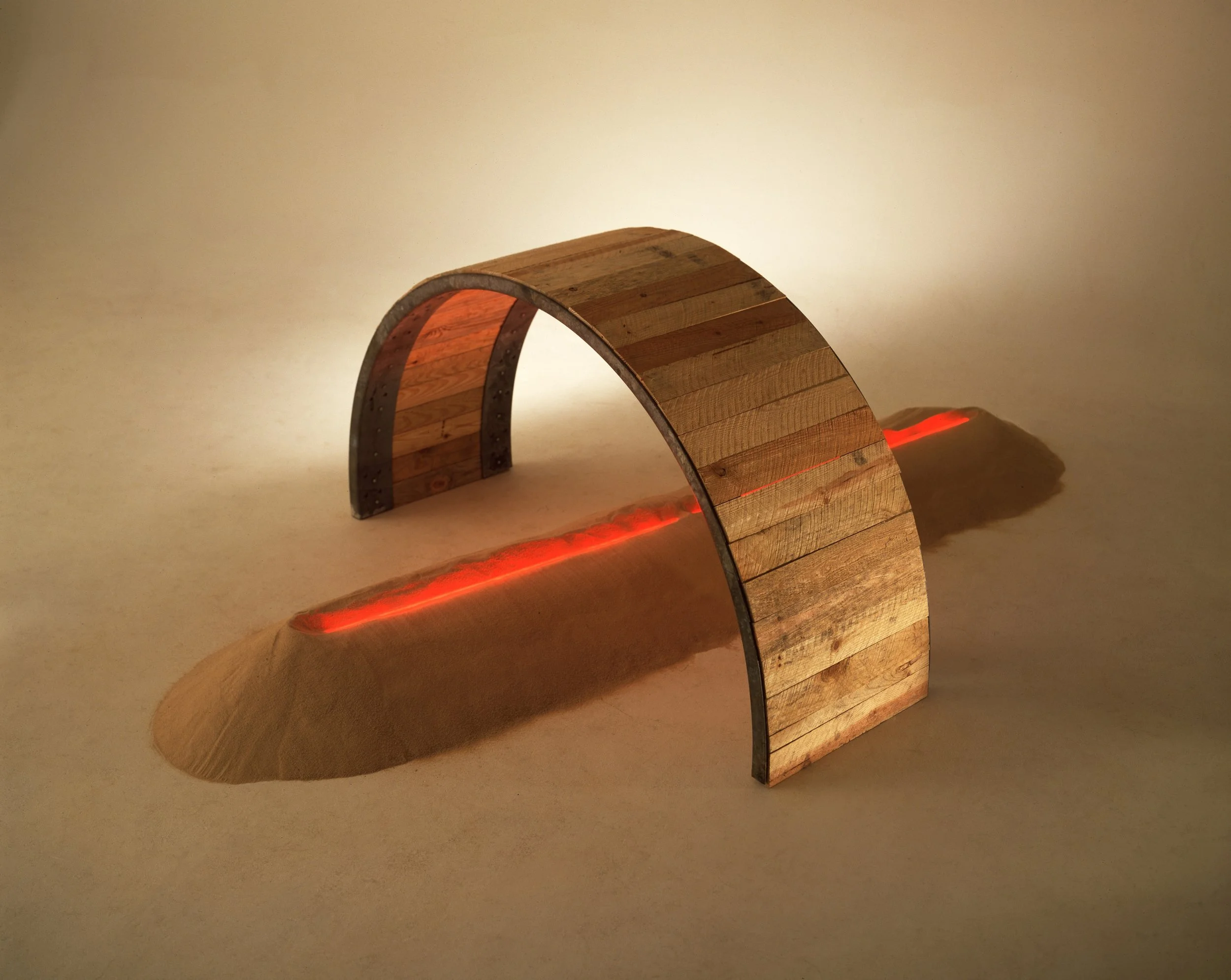 A modern art sculpture consisting of a semi-circular wooden arch with a red LED light strip underneath. The sculpture is set on a plain surface with a neutral background, casting shadows.