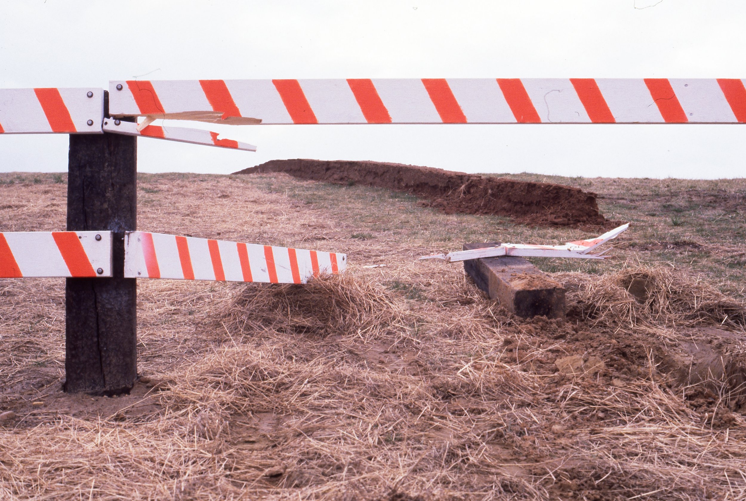 Broken and fallen construction barricade on a dirt ground in an open area.