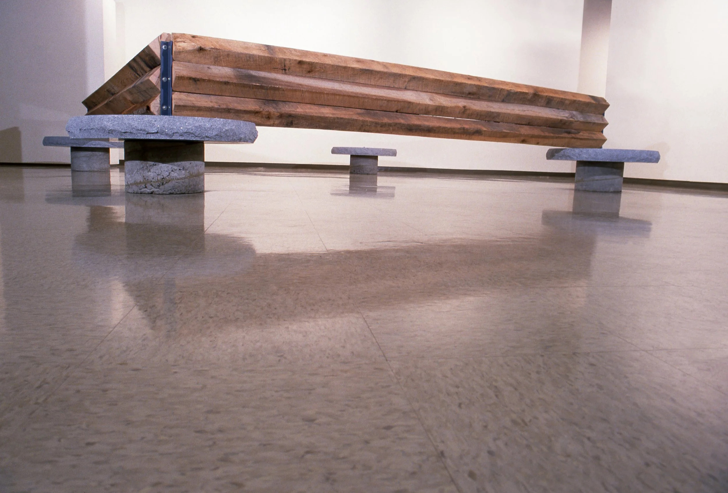 A bench made of wooden planks with concrete supports on a polished floor.