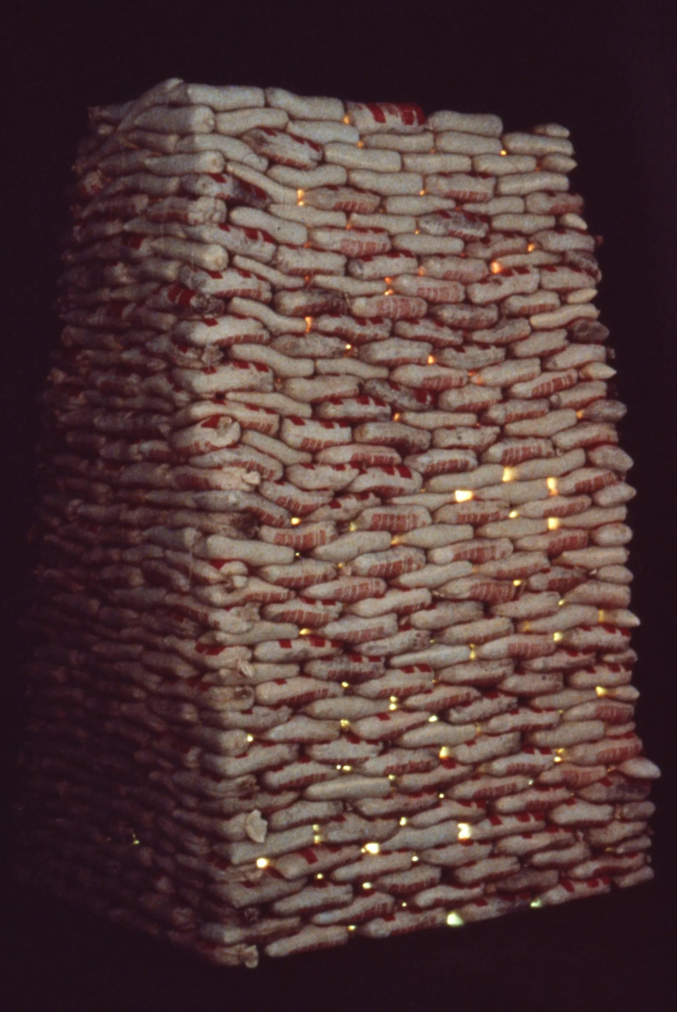 Stack of packaged snack bags with small gaps showing warm light behind.