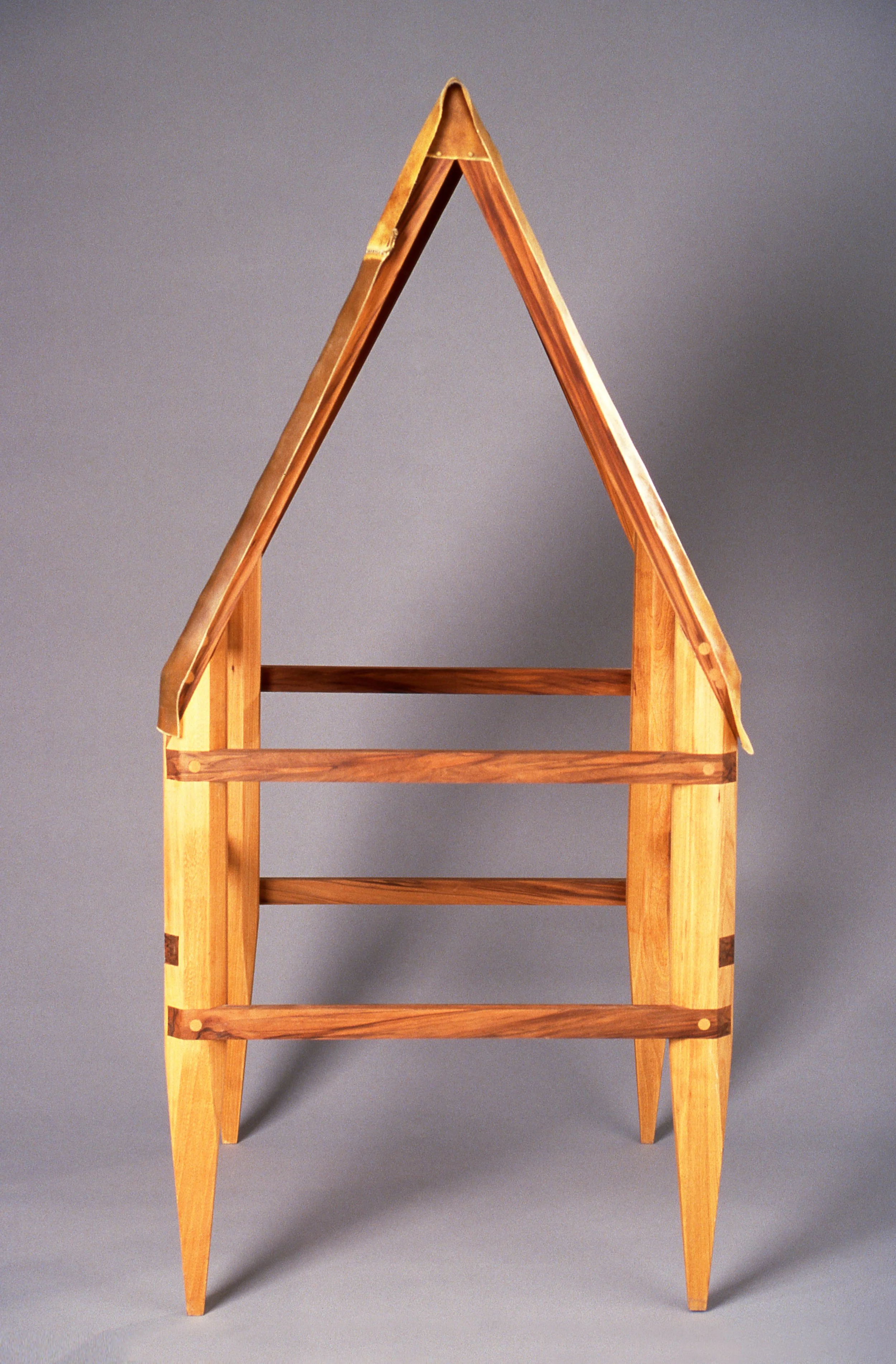 A wooden house-shaped bookshelf with four shelves, consisting of a triangular top and four supporting legs.