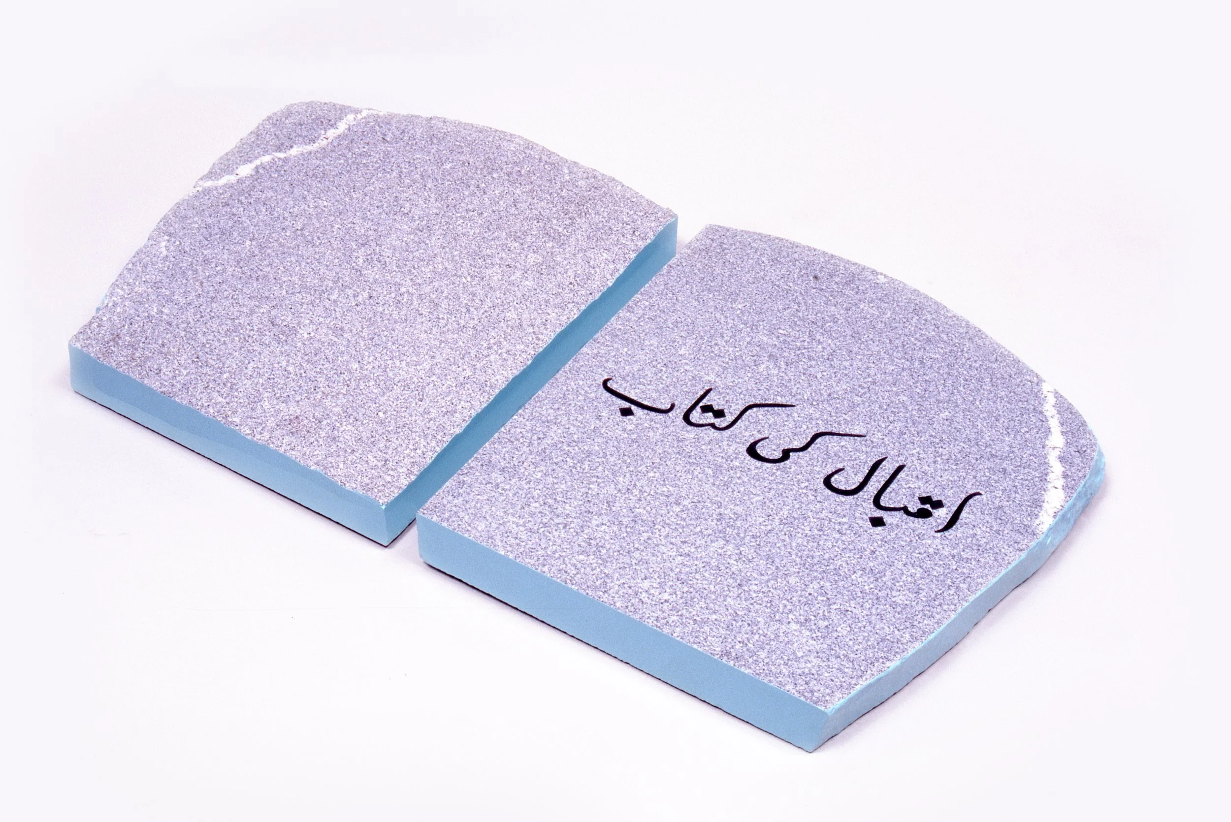A broken ceramic tile with Persian writing on one side, placed on a white background.