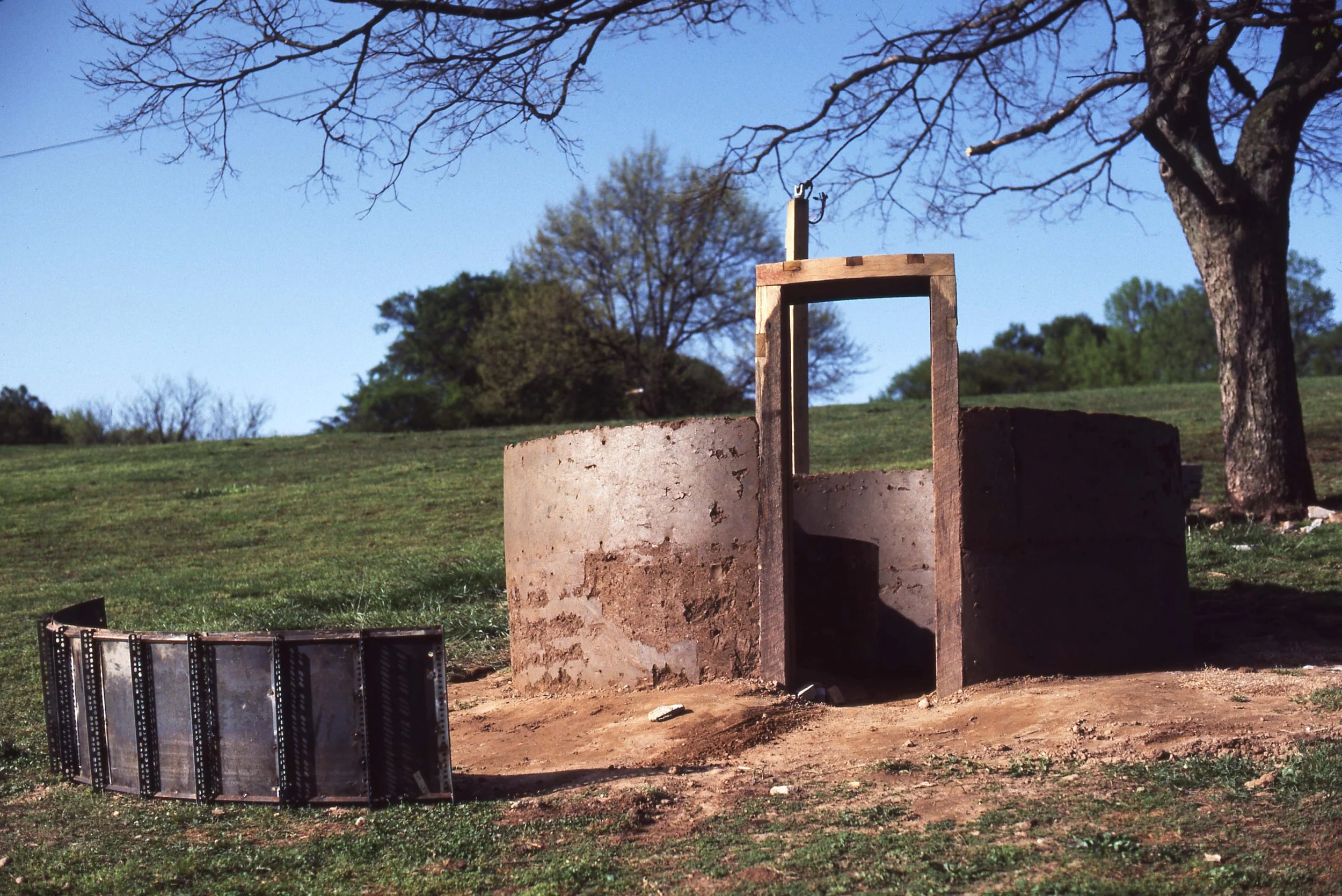 A western-style whiskey still in an open field with trees in the background and a clear blue sky.