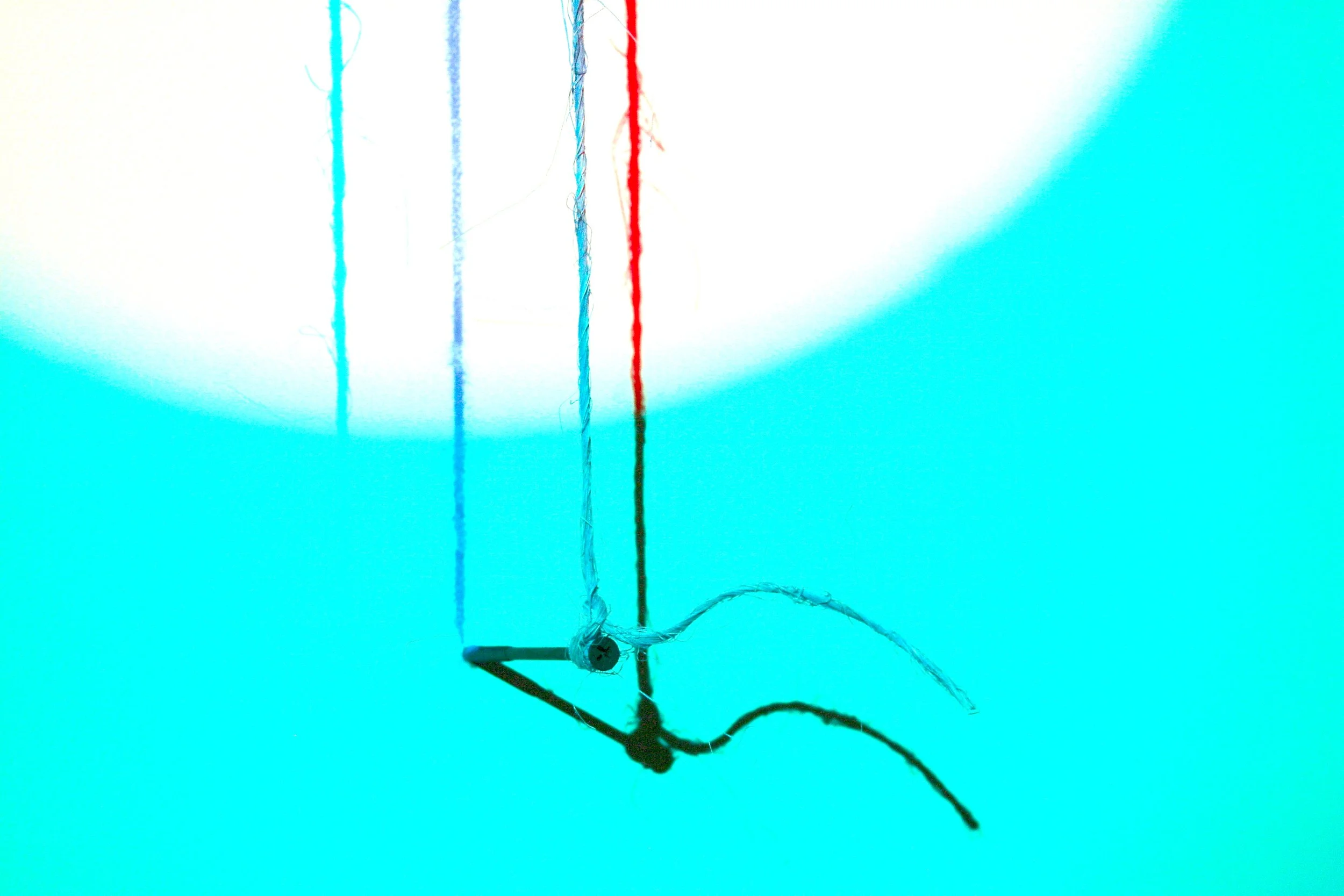 Close-up of a butterfly valve with three color-coded wires (blue, red, green) attached to its shaft, against a bright cyan background.