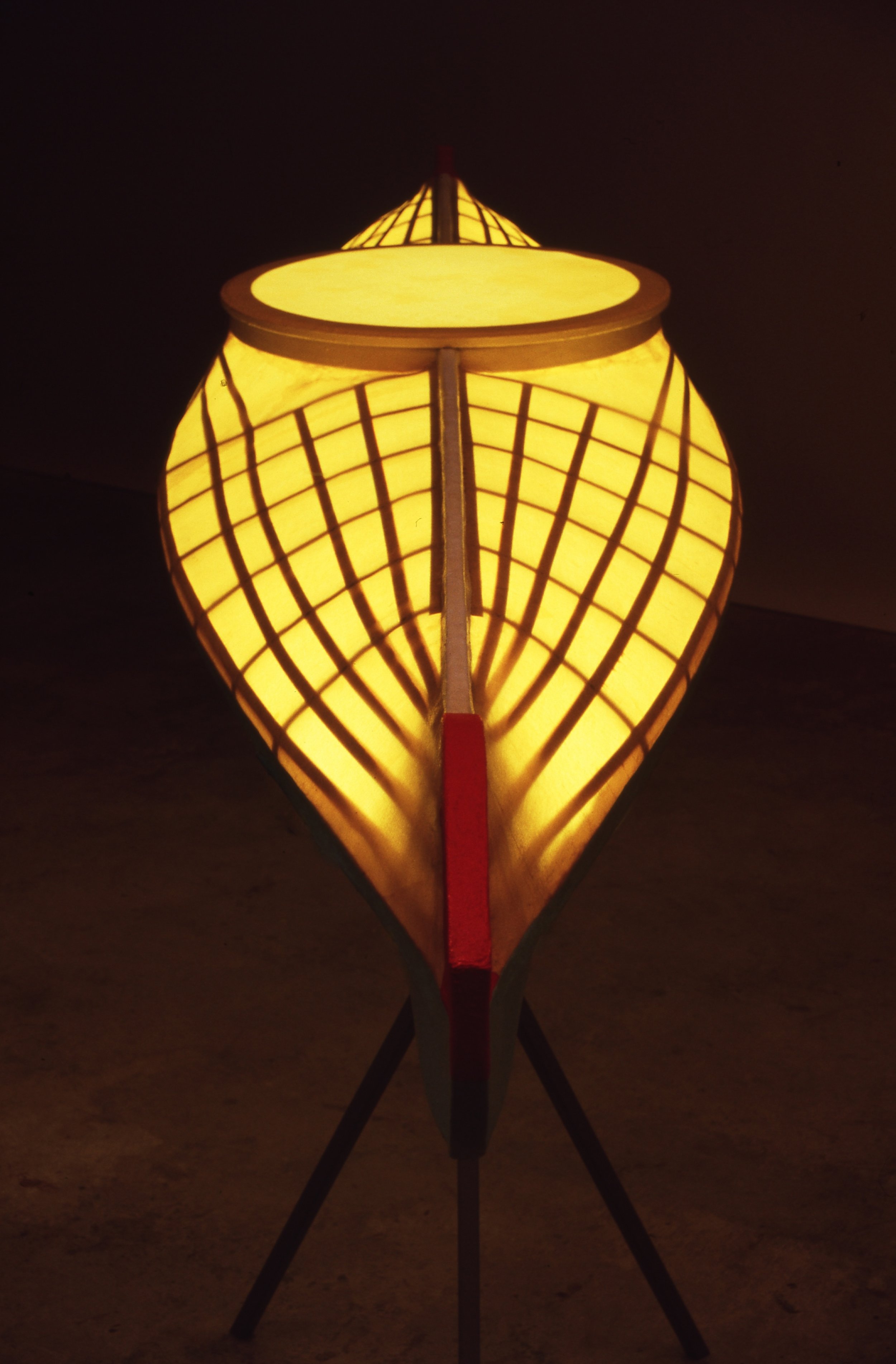 A decorative lamp designed to resemble an upturned boat or vessel with a golden-yellow glow, supported by three black legs.