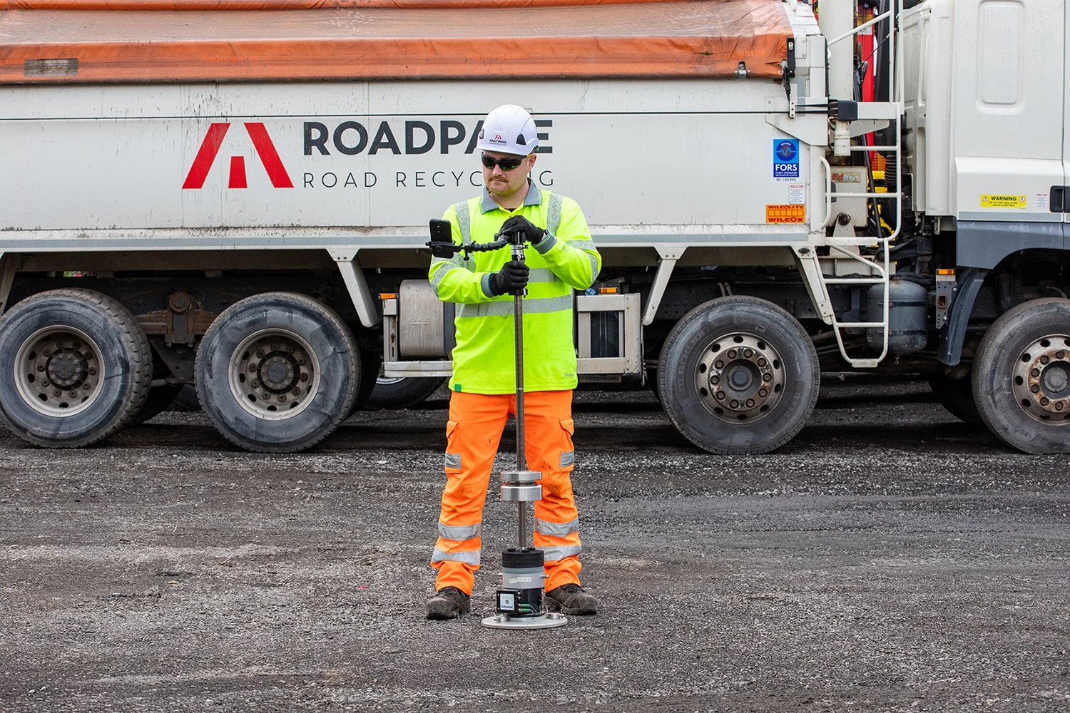 Image of a white male in full PPE using a Lightweight Deflectometer
