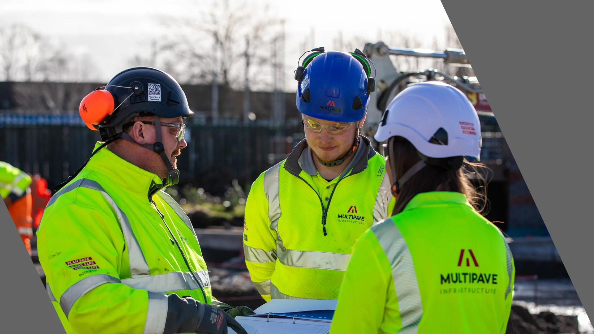 Two males and one female in full PPE talking to each other on site