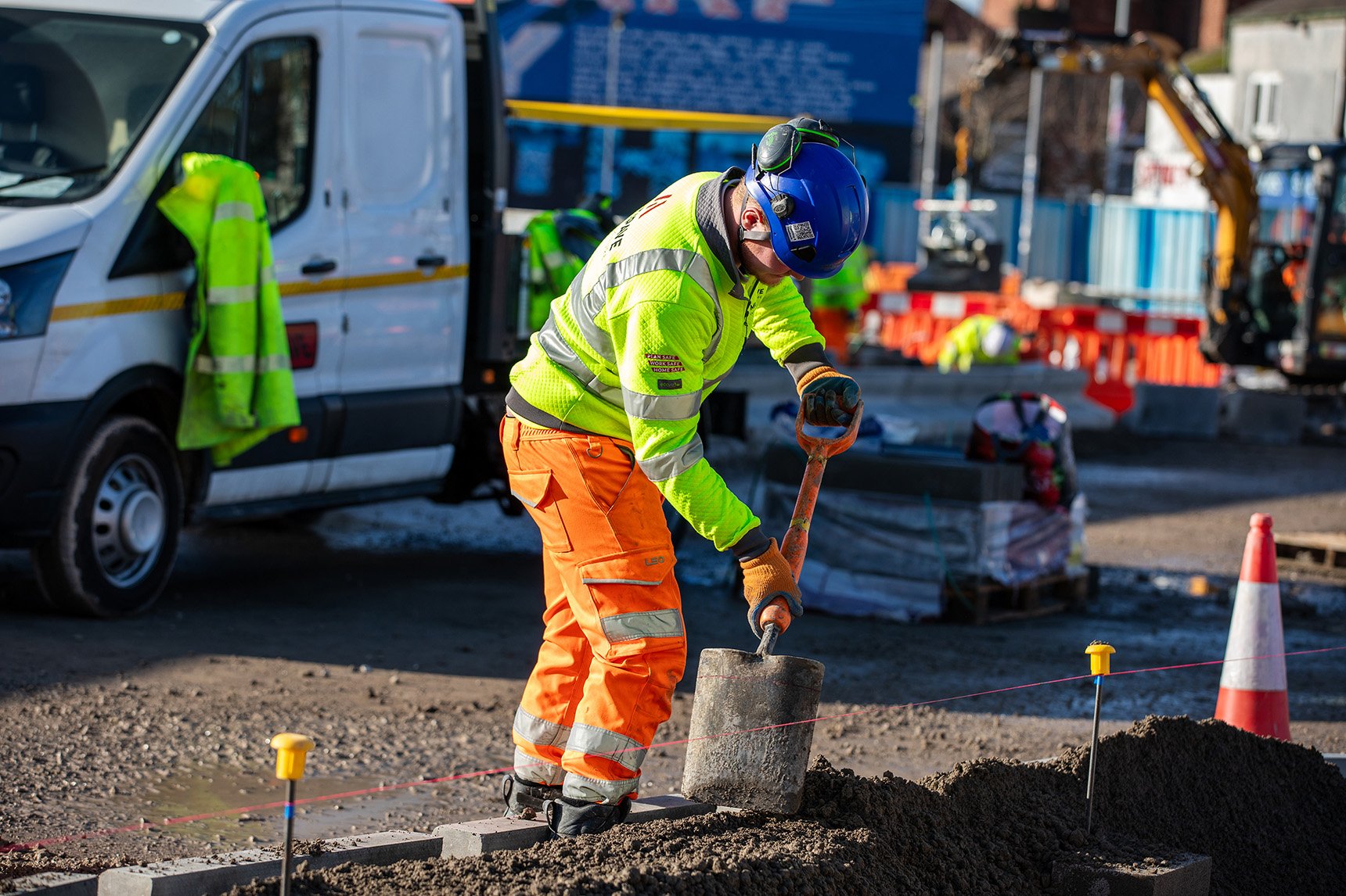 Image of site worker in full PPE using a shovel