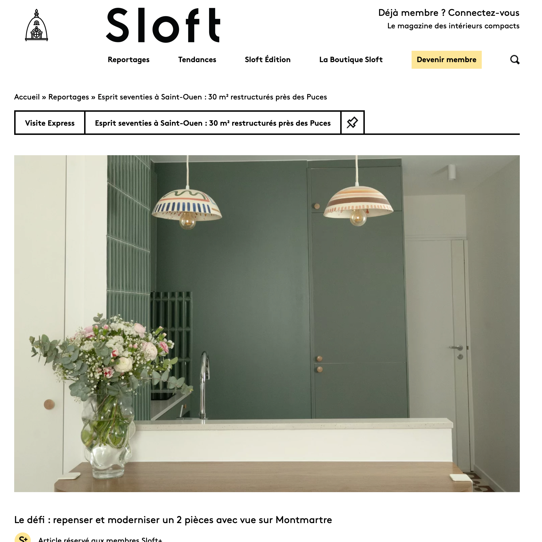 Intérieur moderne avec deux lampes suspendues aux abat-jours colorés, un vase de fleurs sur une table en bois, murs verts et porte blanche