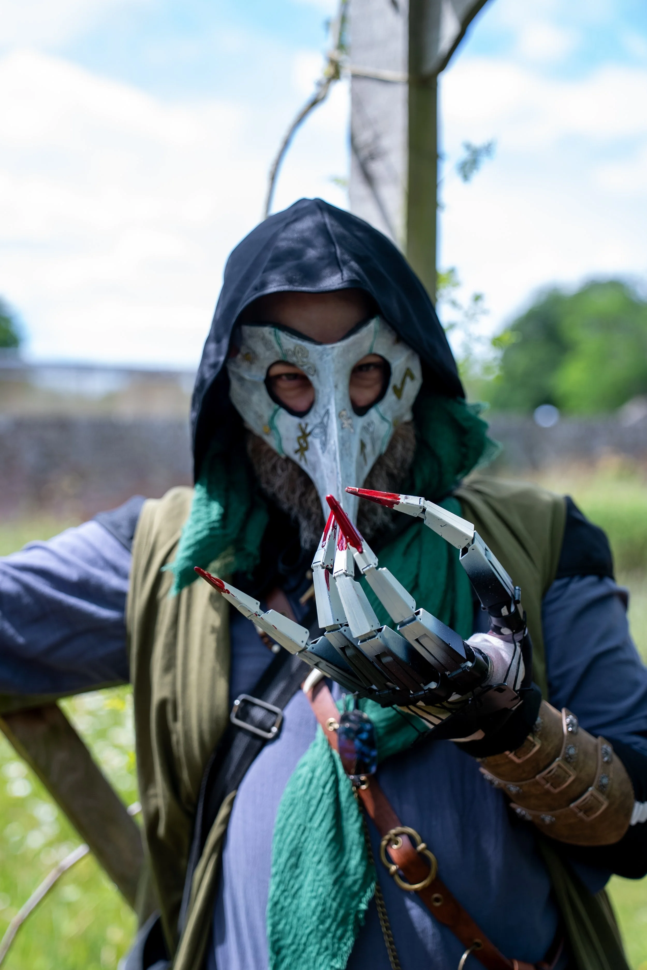 A person wearing a hood, mask and clawed glove.